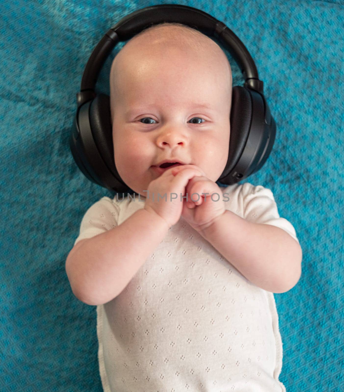 Little boy on blue blanket background with headphones