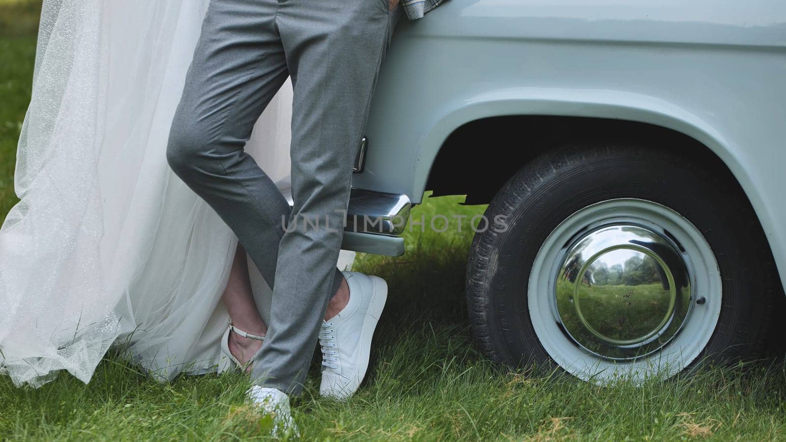 The bride and groom pose by a retro car on their wedding day. by DovidPro