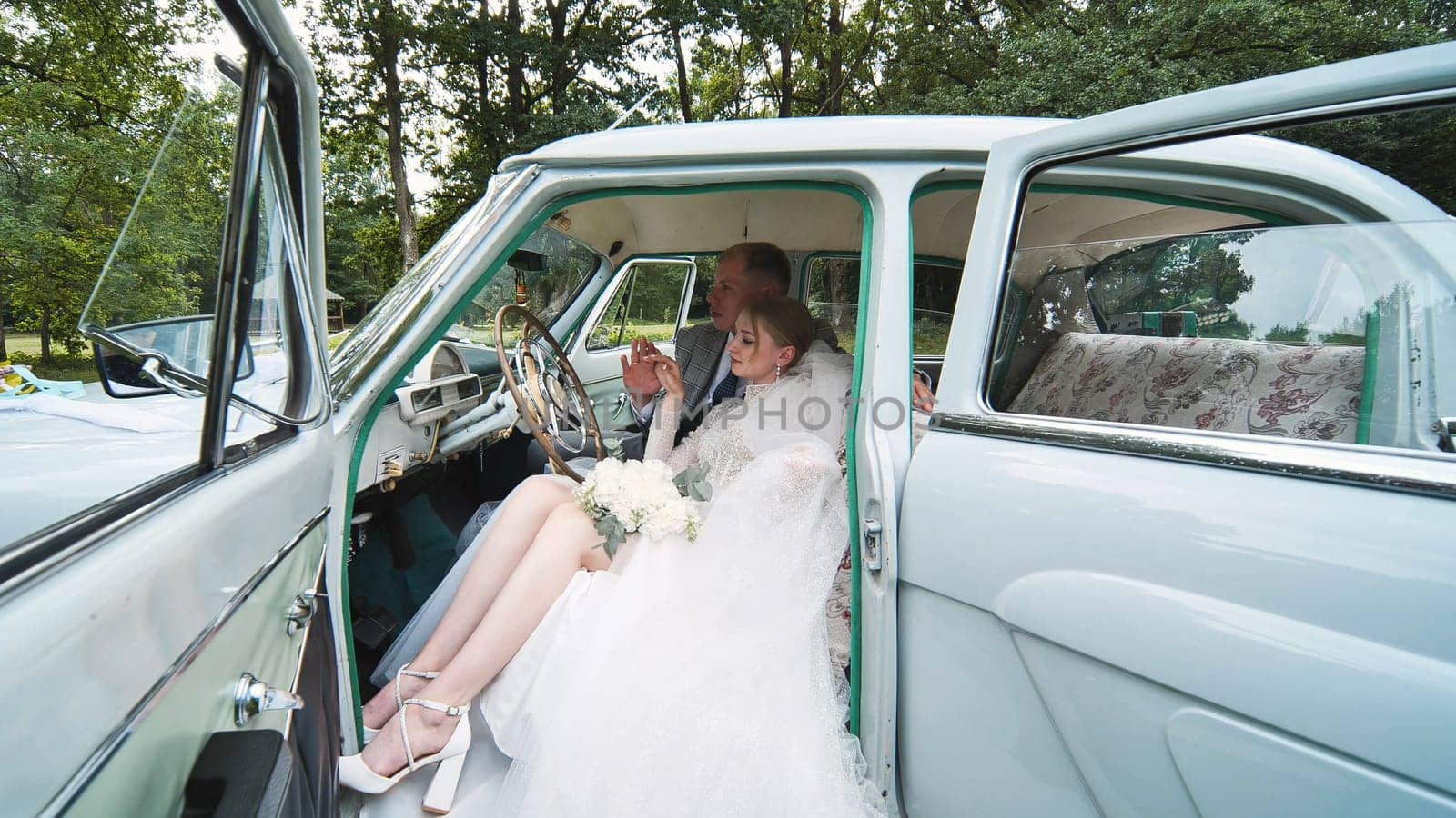 Bride and groom enjoying each other in a retro car. by DovidPro