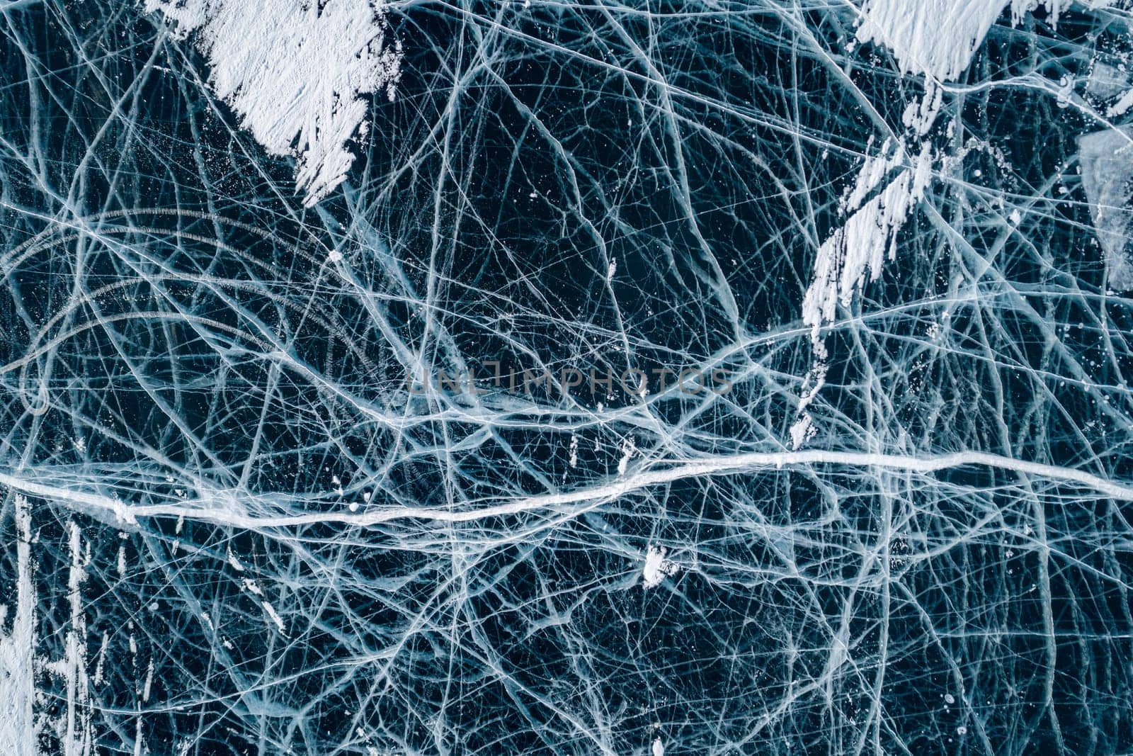 Aerial top down view on the blue cracked ice of the lake Baikal. Winter landscape, frozen lake. Ice kingdom.