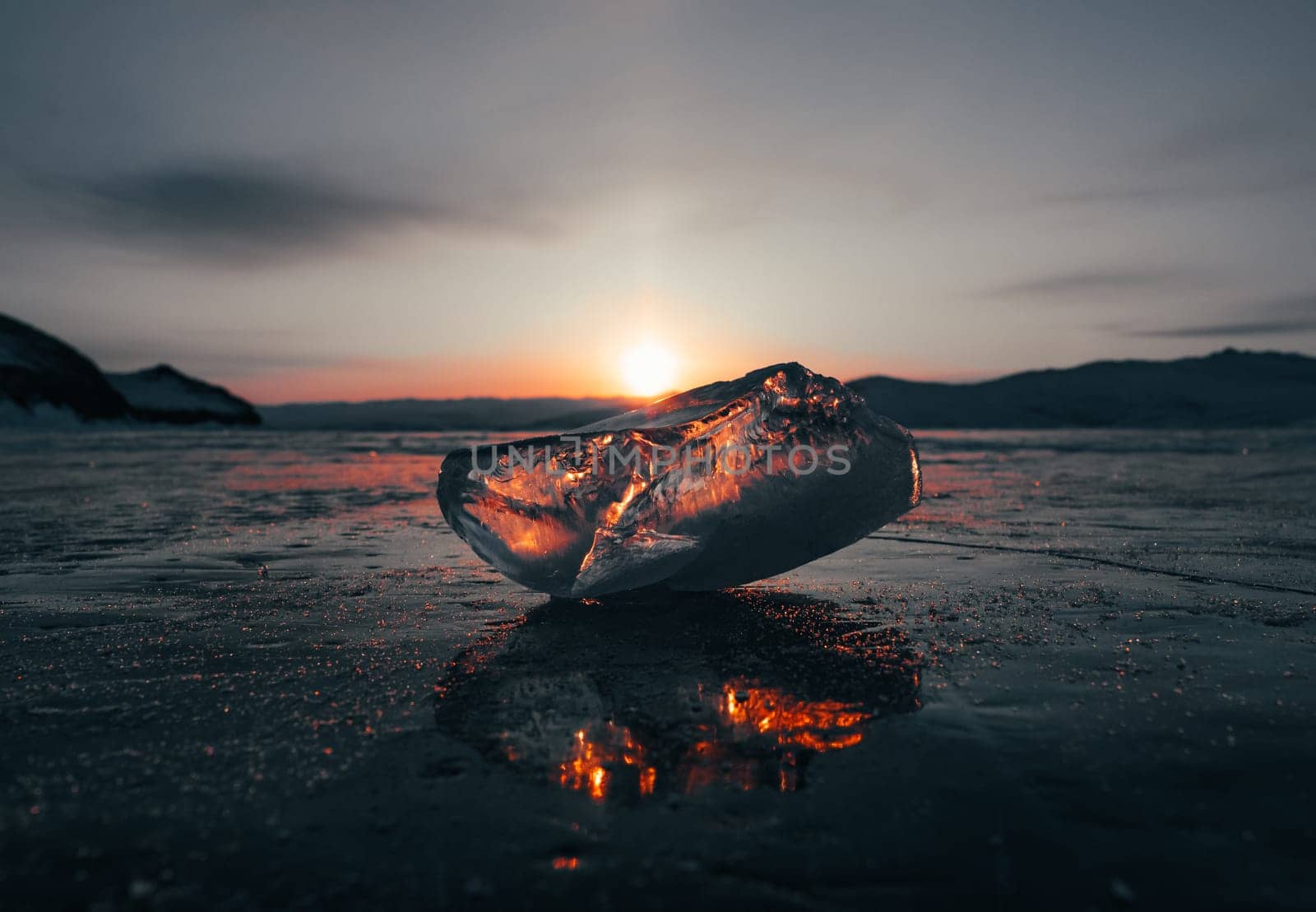 Ice crystal on the frozen surface of Lake Baikal in early morning. Sky and sun reflections on the ice surface. Amazing winter landscape. Winter tourist season at lake Baikal by Busker