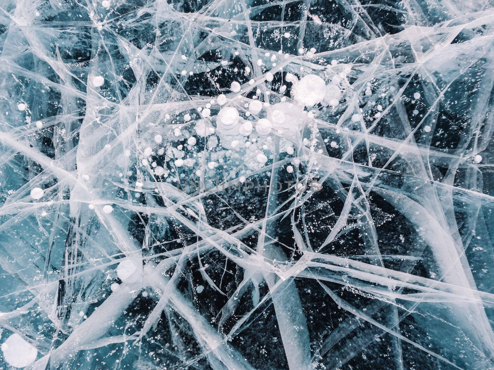 Blue snowy cracked ice of the lake Baikal. Winter landscape of frozen Baikal. Popular tourist spot by Busker