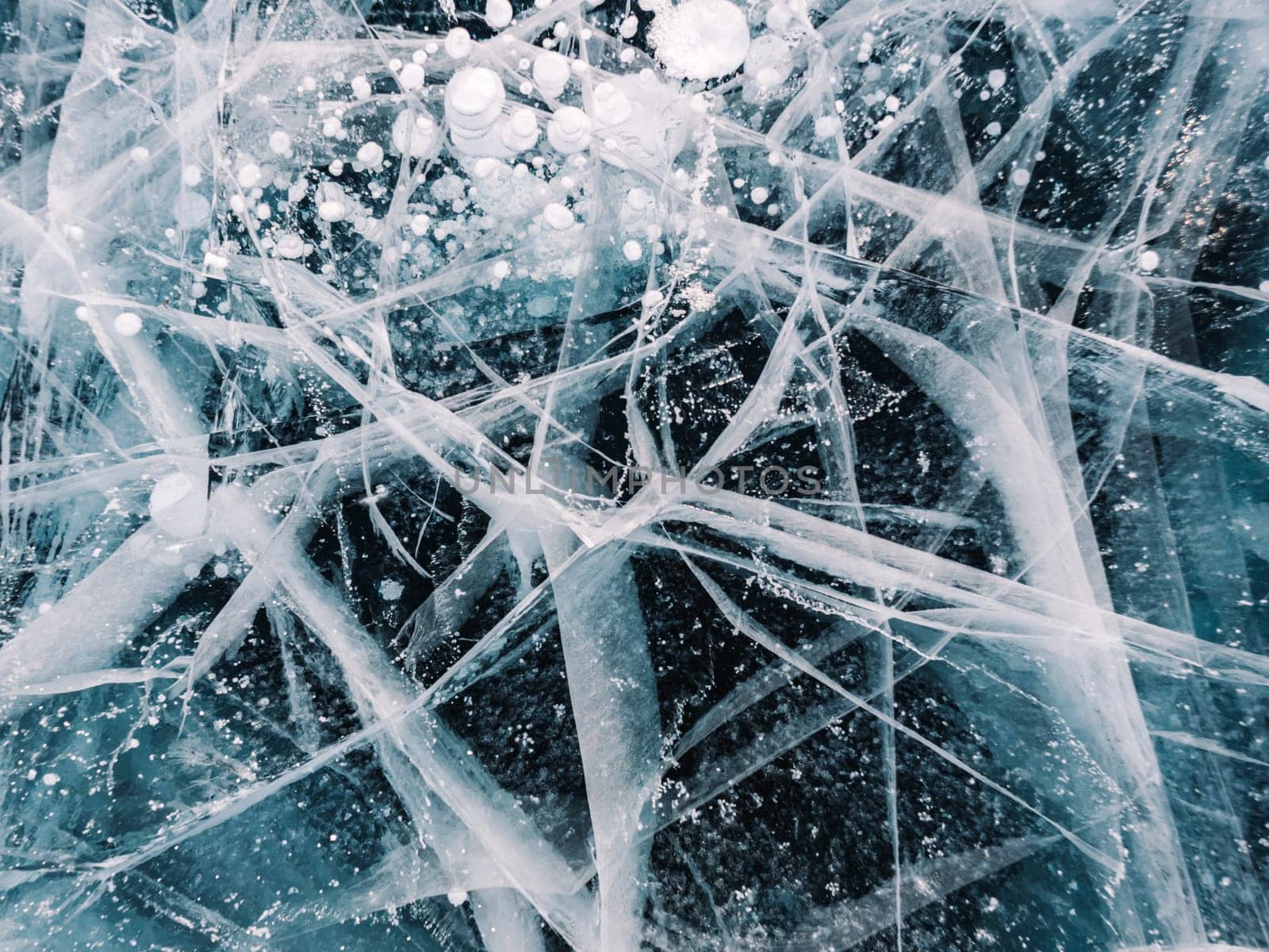 Blue snowy cracked ice of the lake Baikal. Winter landscape of frozen Baikal. Popular tourist spot by Busker