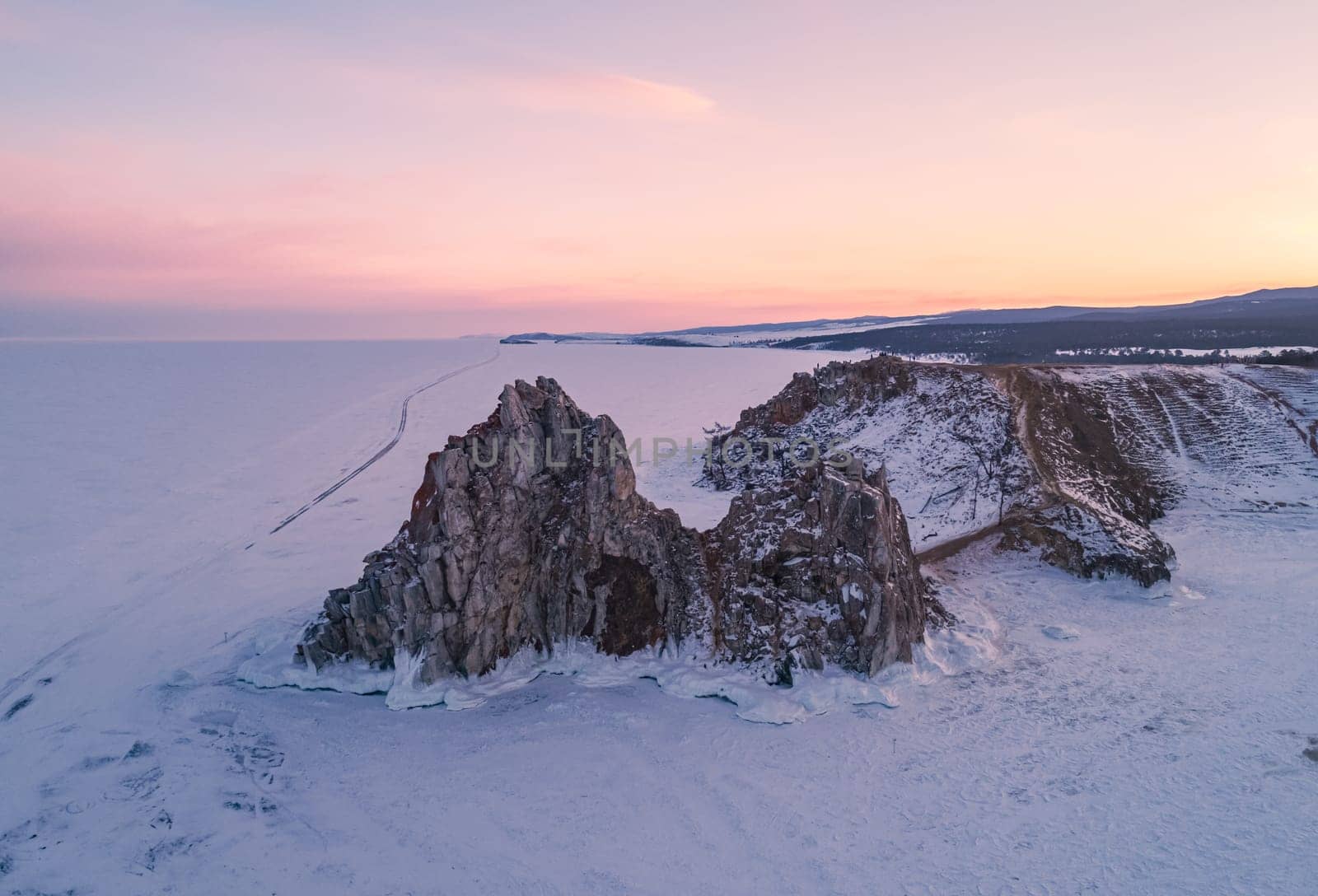 Aerial shot of a Shamanka rock on Olkhon island at sunset. Winter landscape. Popular touristic destination. Natural landmark. Panoramic view by Busker