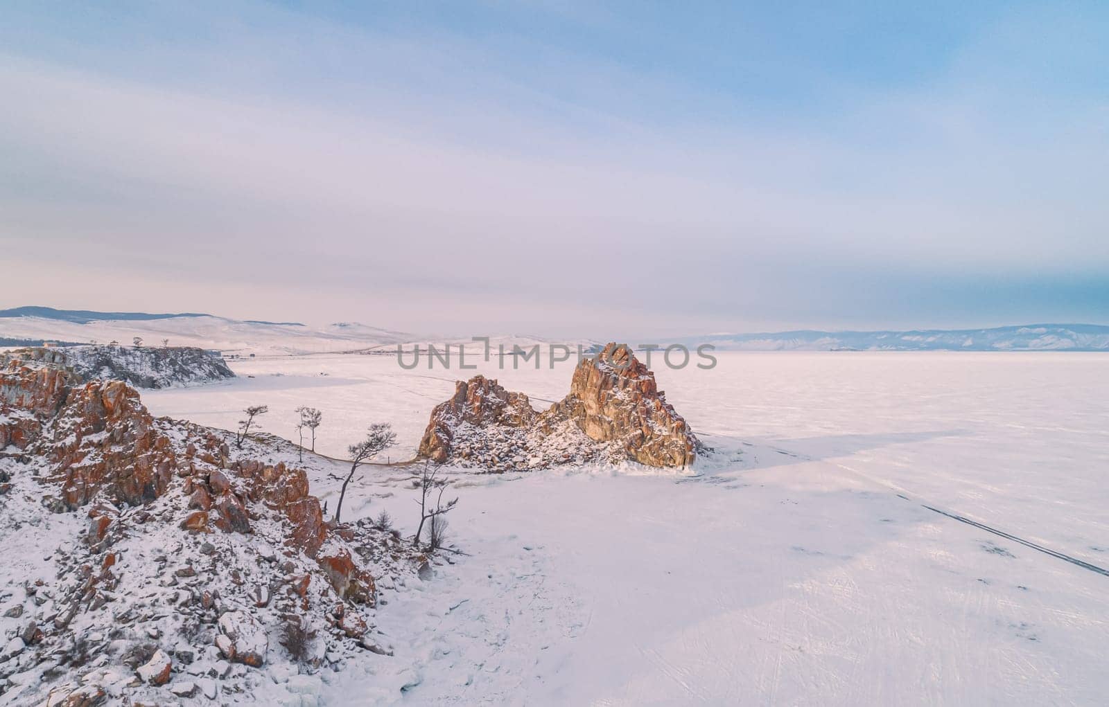 Aerial shot of a Shamanka rock on Olkhon island at sunset. Winter landscape. Popular touristic destination. Natural landmark. Panoramic view by Busker