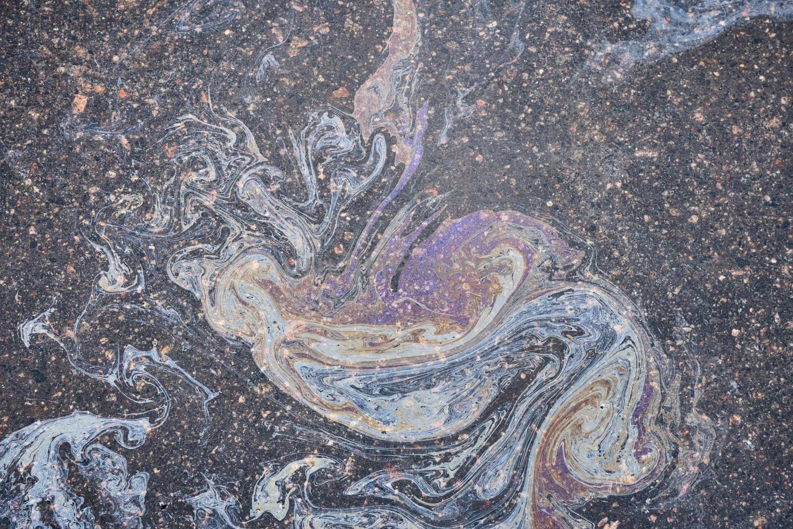 Colored oil stains close-up, color of a gasoline stain on asphalt as a texture or background.