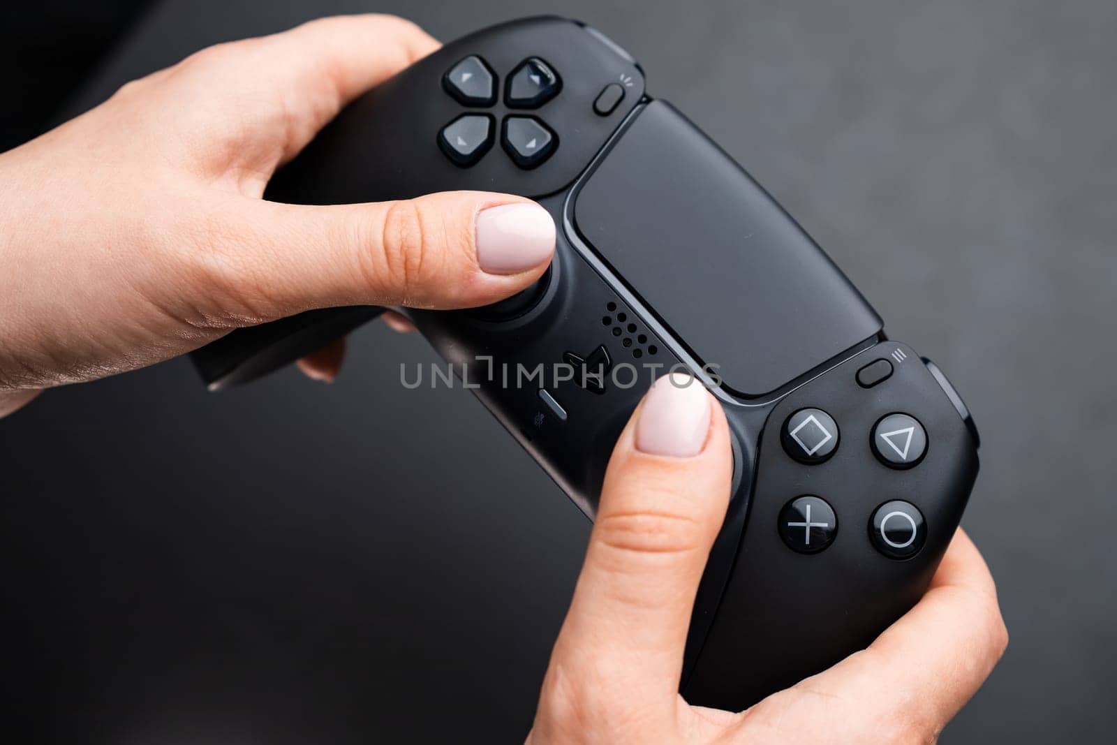 BERLIN , GERMANY - FEBRUARY 14 2024: Nex generation game controller in womans hand on the black background