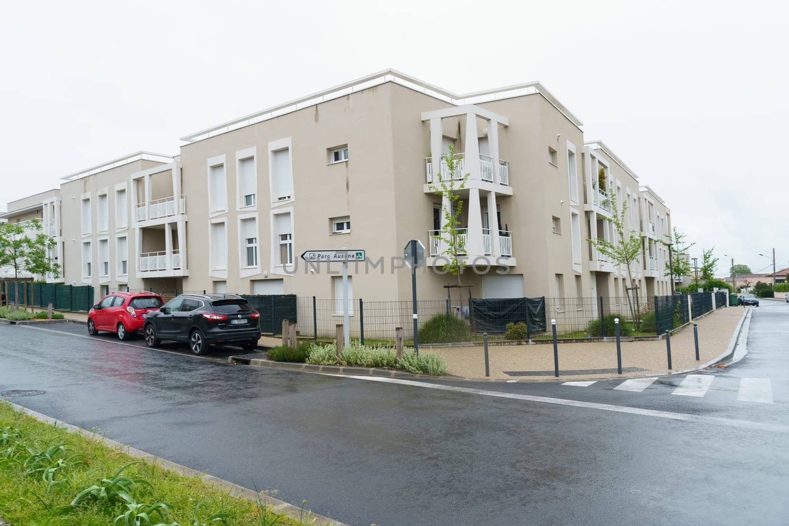 Bordeaux, France - April 26, 2023: Cars parked neatly along the side of a busy urban street with buildings in the background.