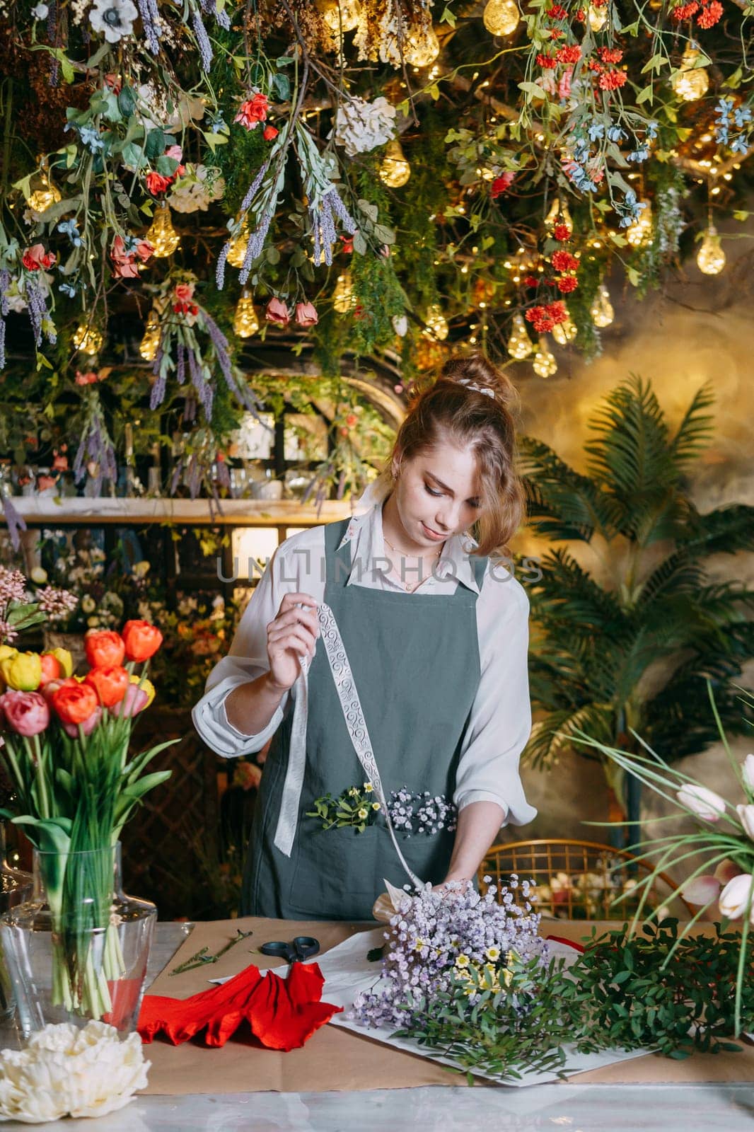 A woman in her florist shop collects bouquets of flowers. The concept of a small business. Bouquets of tulips for the holiday on March 8