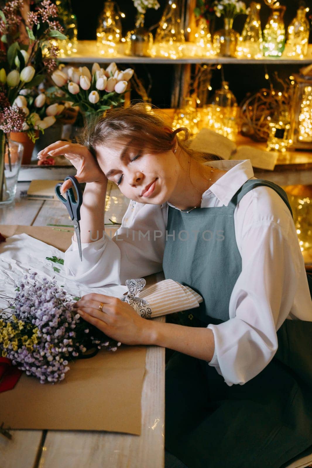 A woman in her florist shop collects bouquets of flowers. The concept of a small business. Bouquets of tulips for the holiday on March 8. by Annu1tochka