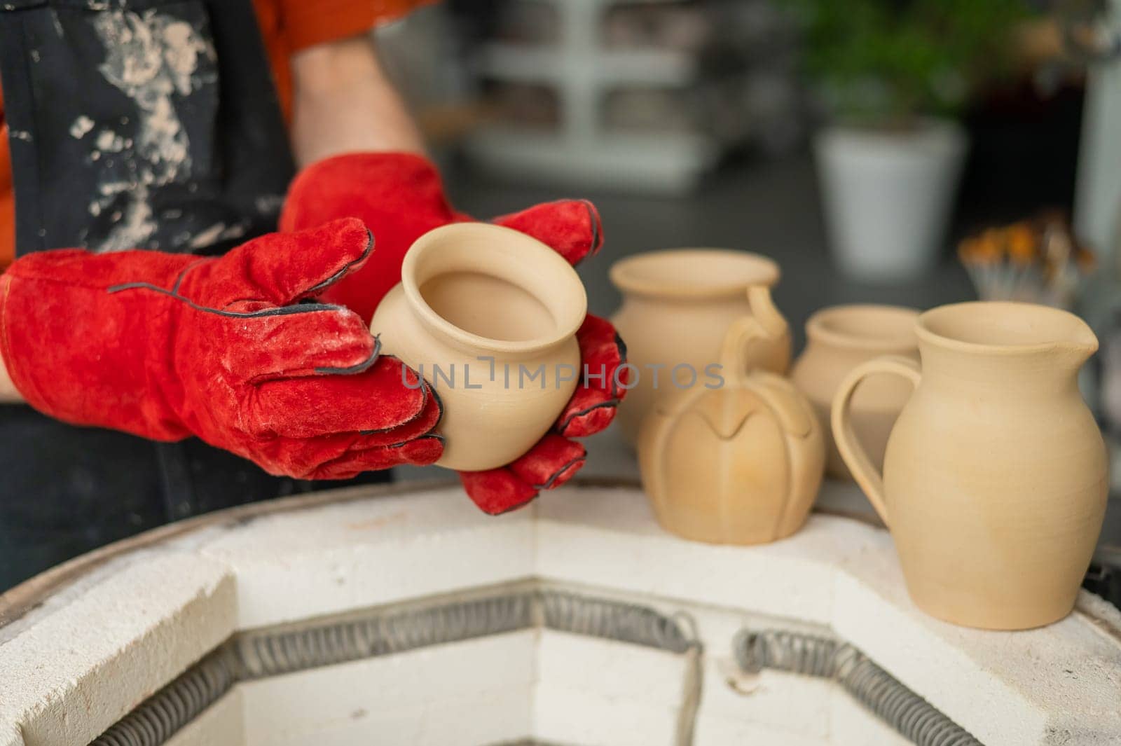 Close-up of a man's hands loading ceramics into a special kiln. by mrwed54