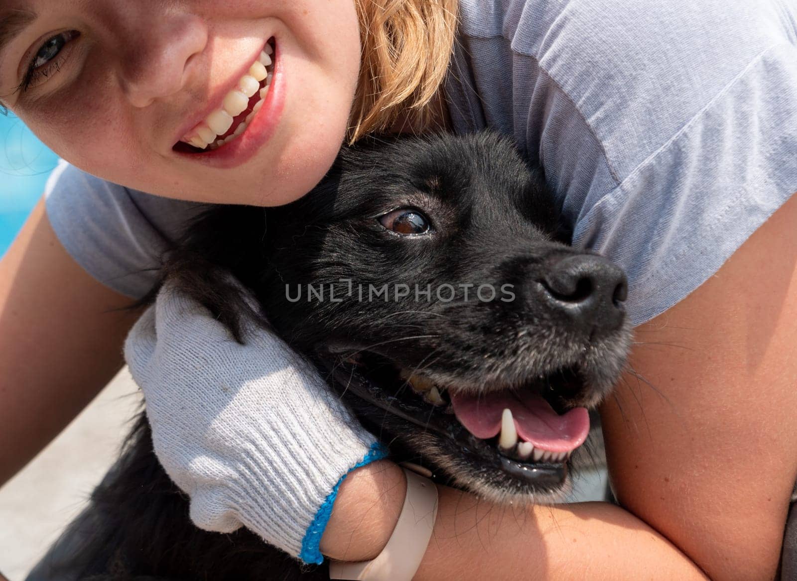 Young girl hugging and petting caged stray dog in pet shelter. People, Animals, Volunteering And Helping Concept. by Busker