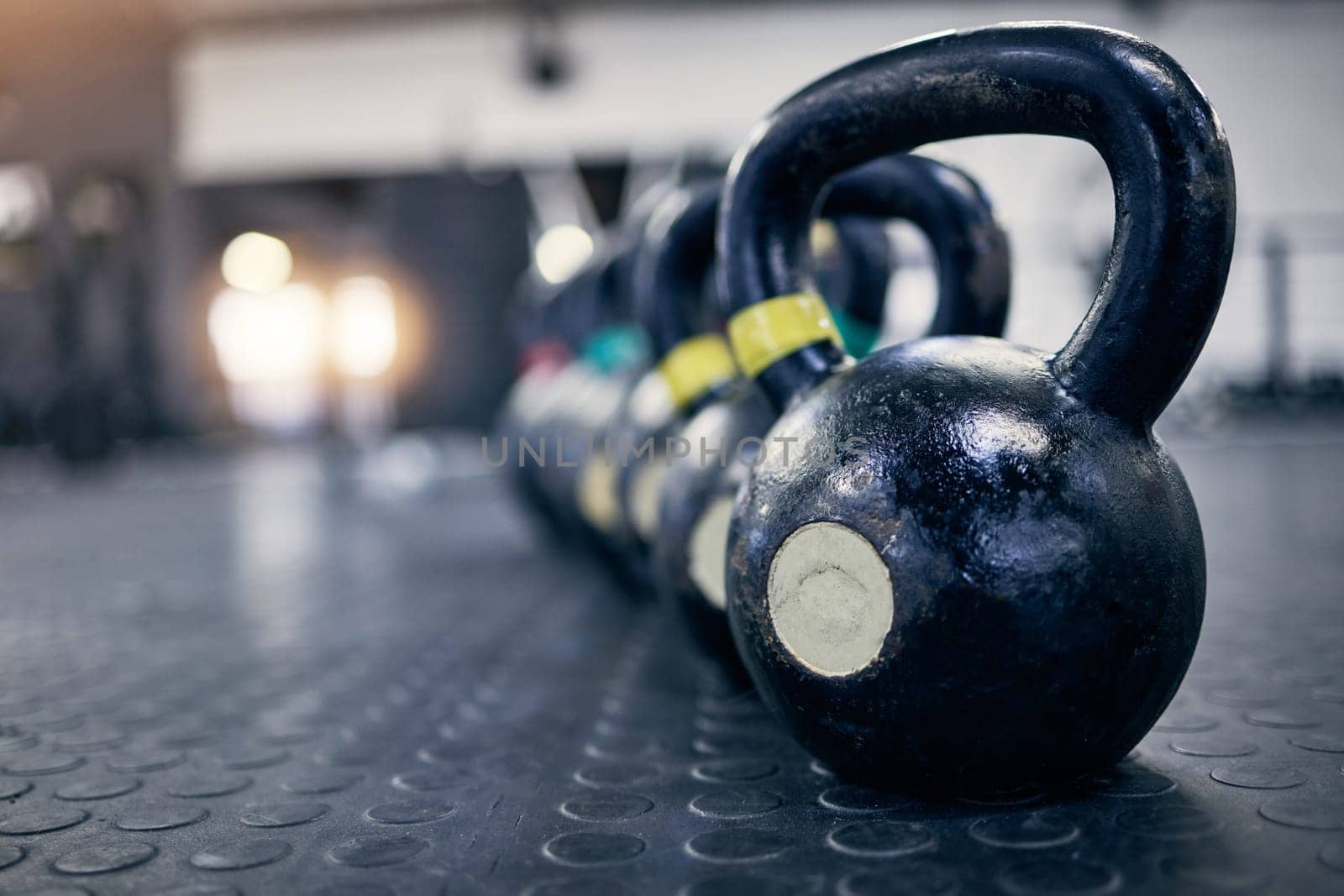 Exercise, kettlebell and weights on floor of gym for training, wellness or workout with space. Background, metal equipment in health club and fitness for action, physical improvement or strength by YuriArcurs