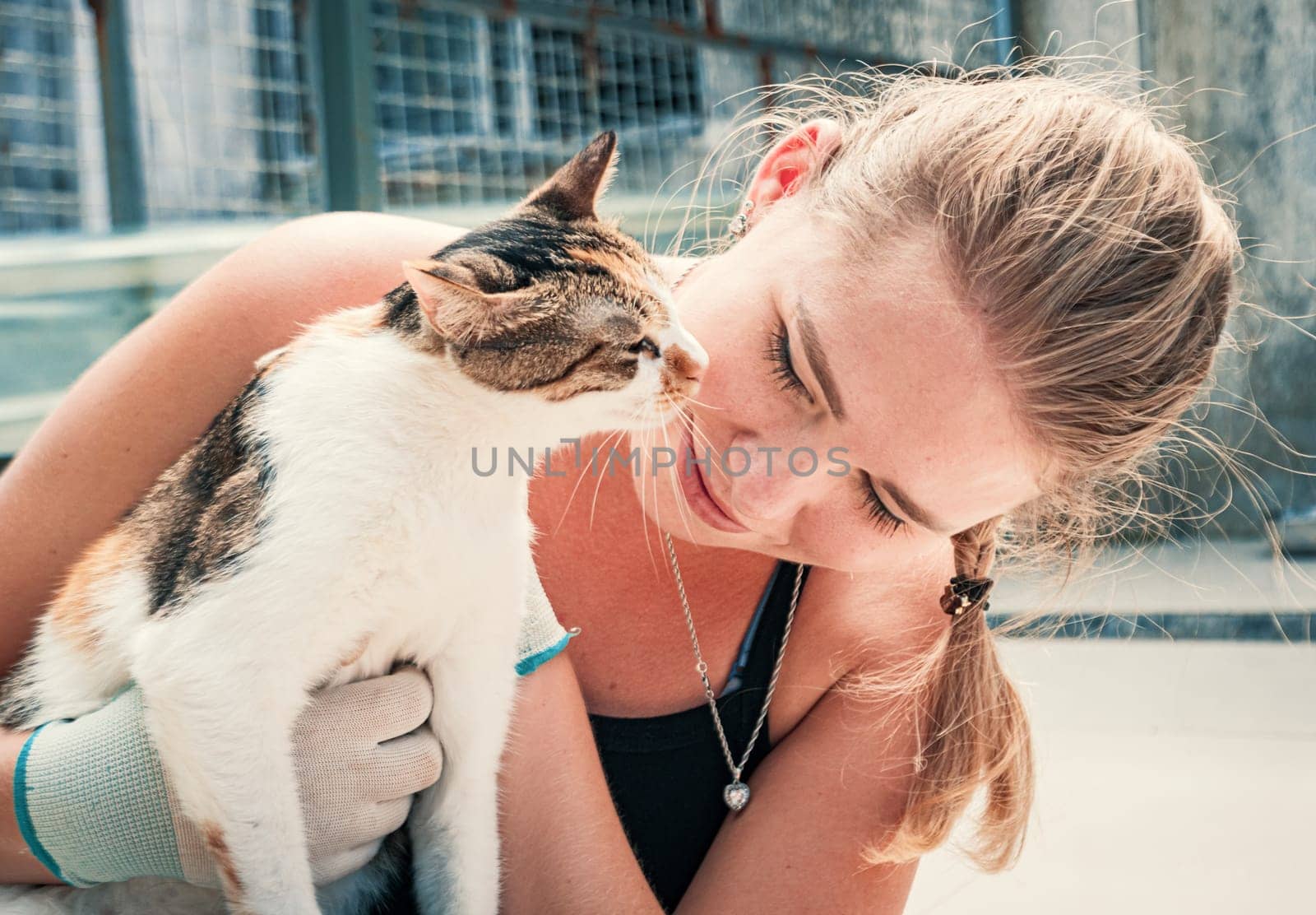 Female volunteer hugs cat in shelter