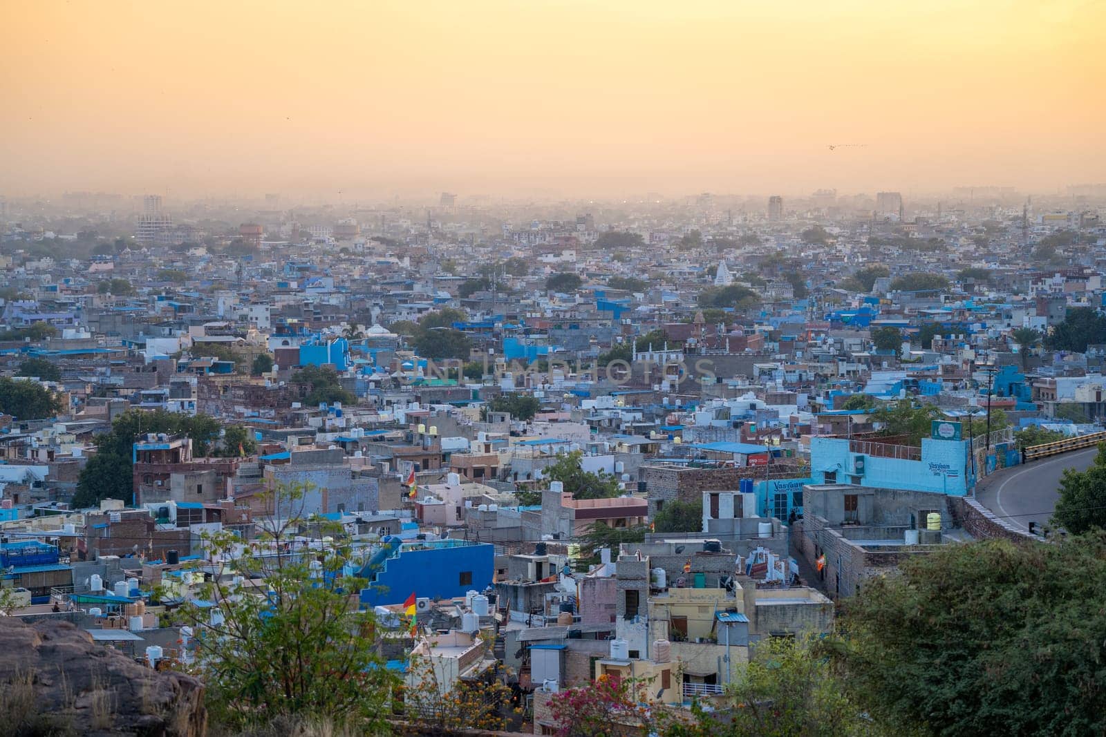 aerial drone shot at dusk sunset showing jodhpur blue city cityscape showing traditional houses in middle of aravalli with colorful densely packed houses by Shalinimathur