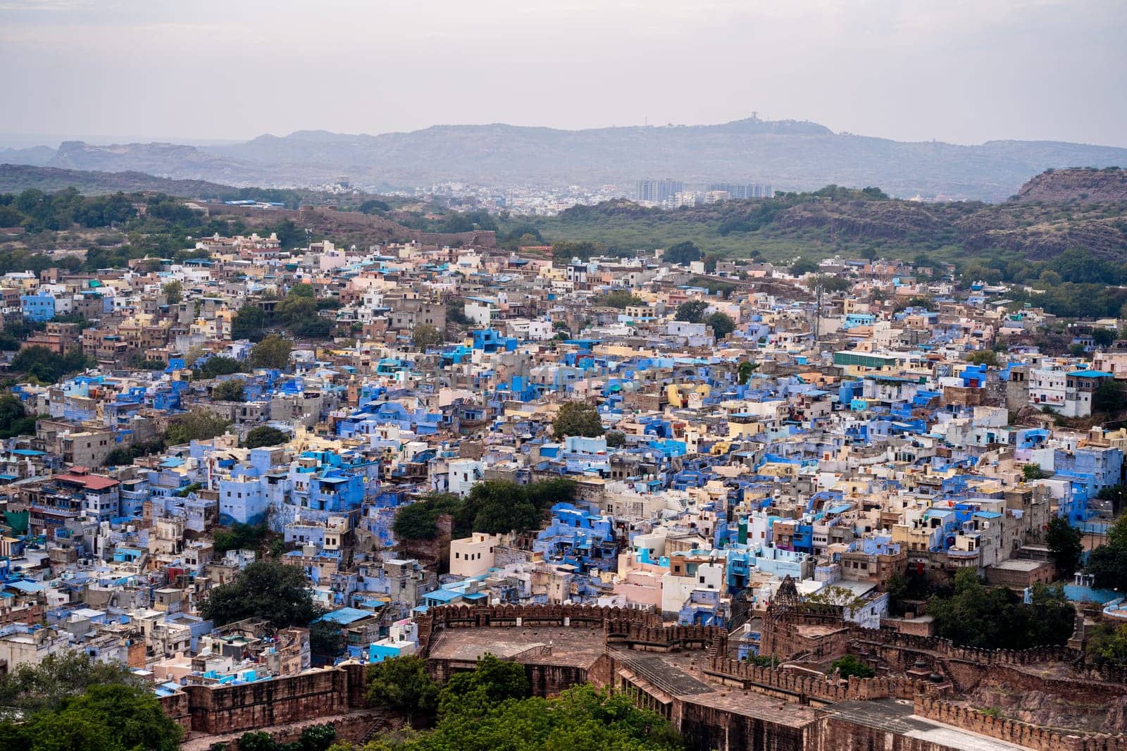 aerial drone shot showing jodhpur blue city cityscape showing traditional houses in middle of aravalli with colorful densely packed houses by Shalinimathur