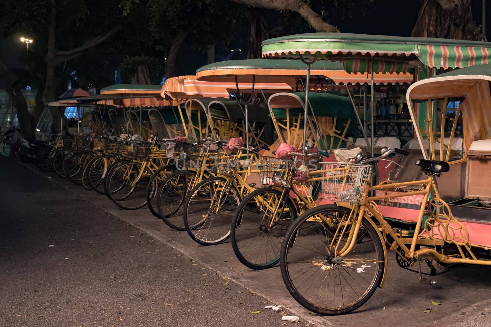 Empty typical chinese rickshaws on night street of Macau by Busker