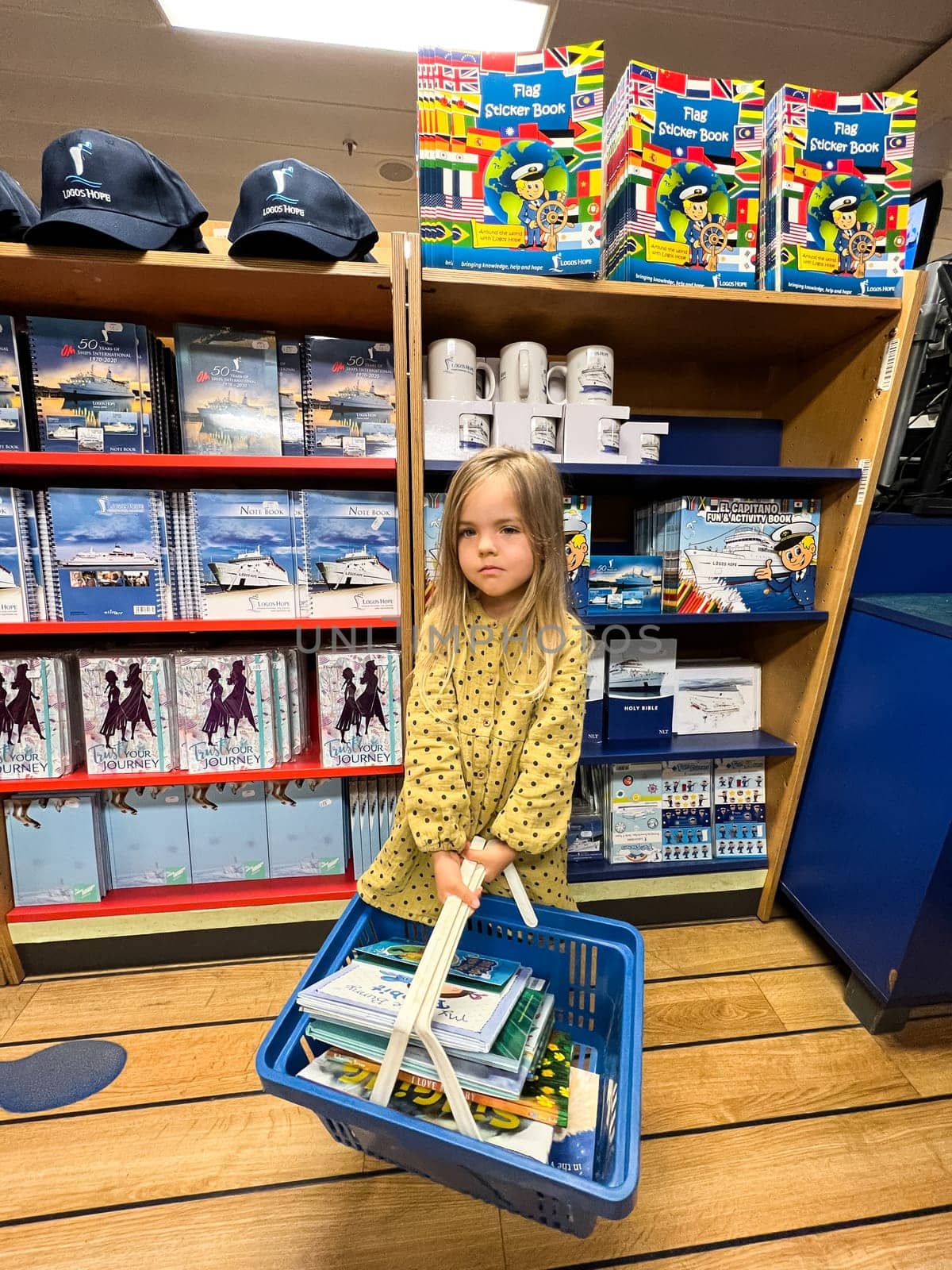 Little girl with a basket of books stands in a bookstore. High quality photo