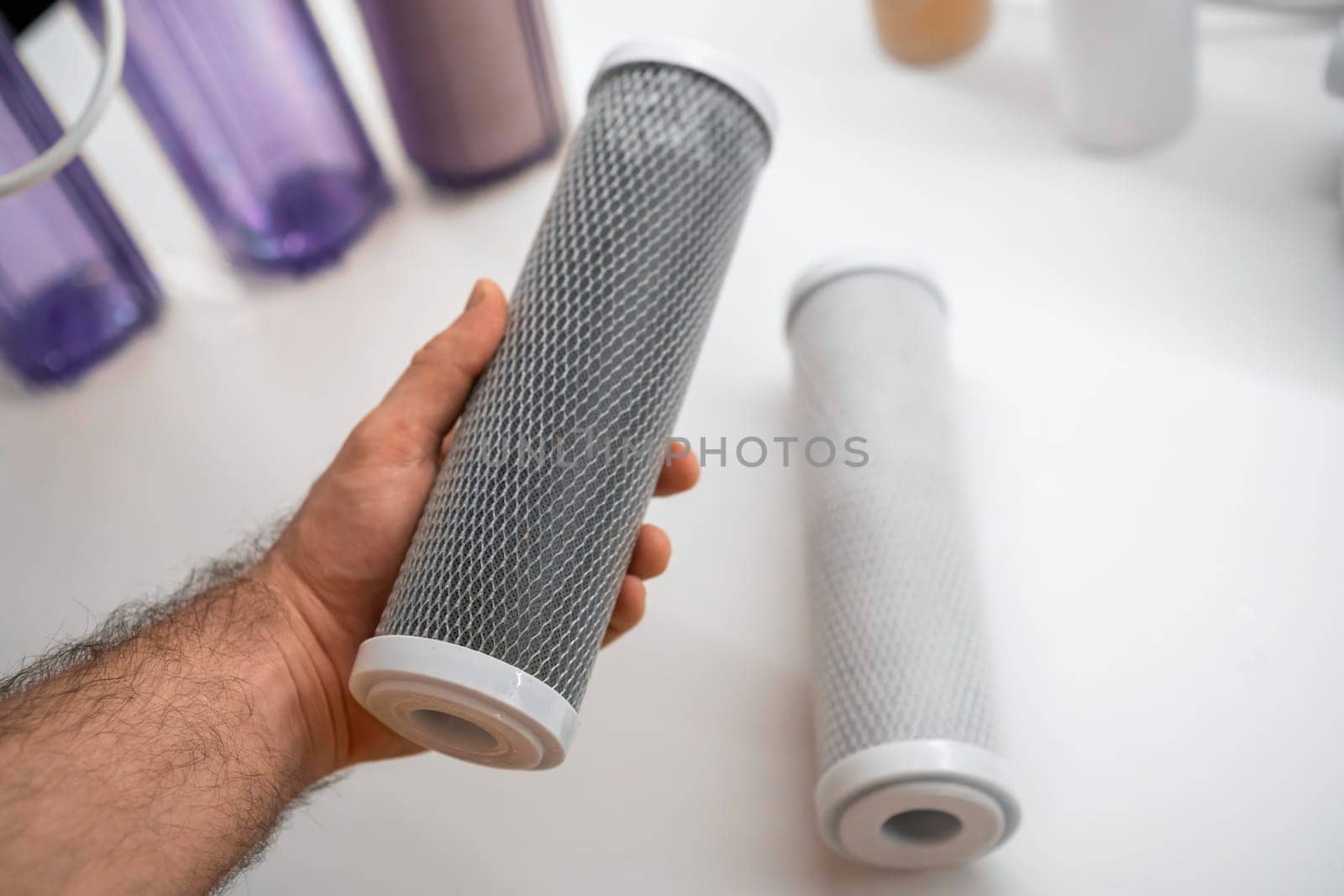 Man replacing the carbon filter in the reverse osmosis system on the table