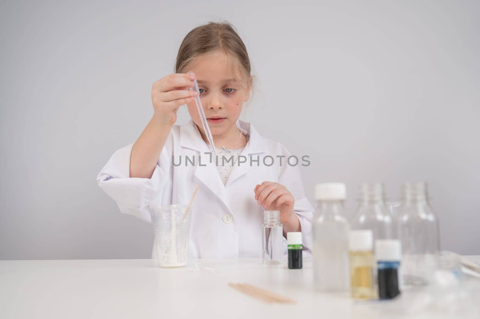 Caucasian girl doing chemical experiments on a white background. by mrwed54