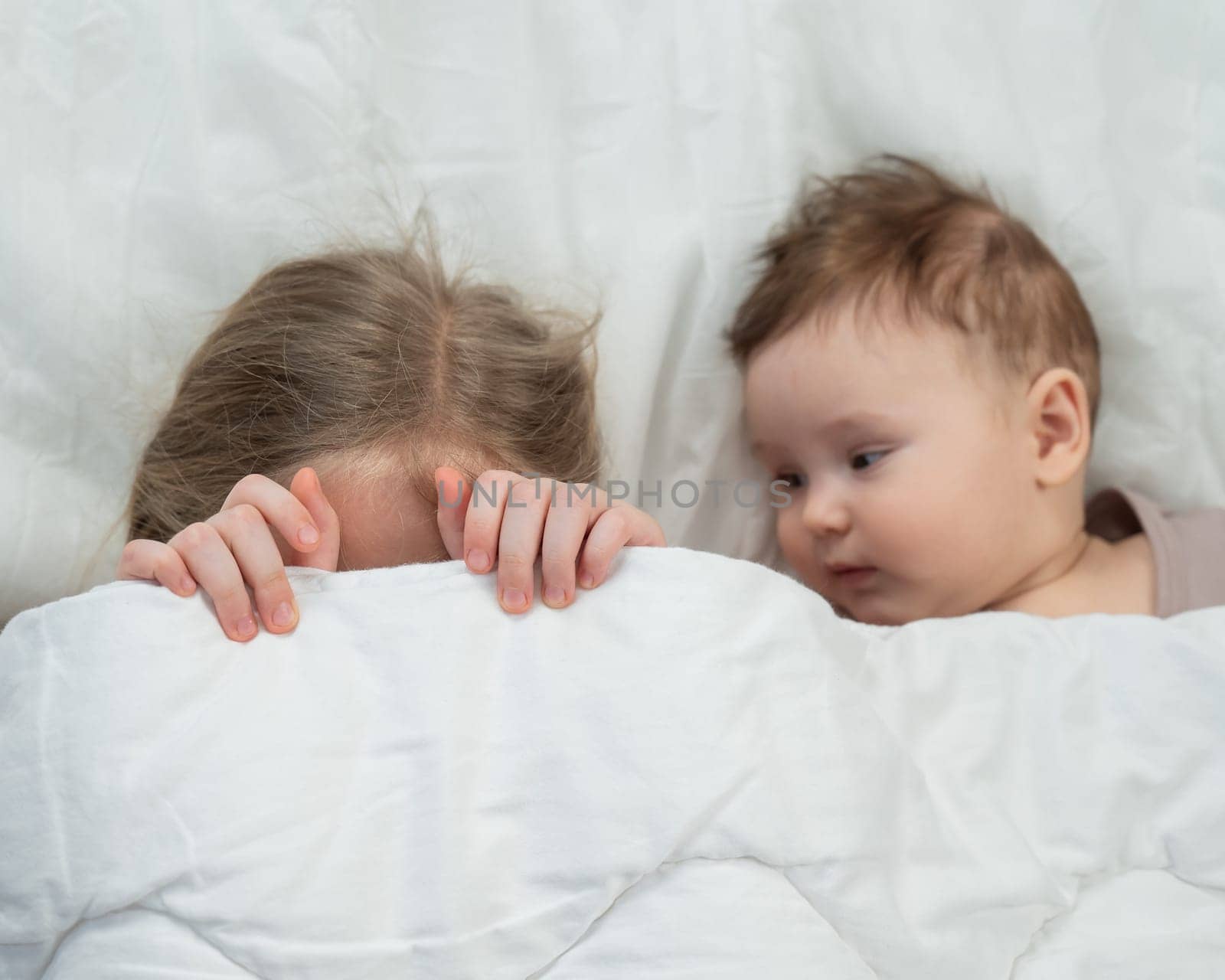 Top view of a little boy and his six year old sister lying under a blanket