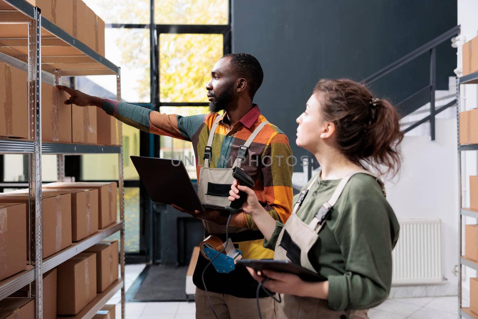 Diverse storehouse employees checking cardboard boxes, scanning products for inventory using store scanner in warehouse. Stockroom supervisors working at clients orders preparing packages for delivery