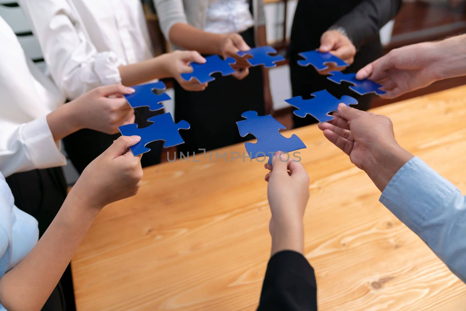 Multiethnic business people holding jigsaw pieces and merge them together as effective solution solving teamwork, shared vision and common goal combining diverse talent. Meticulous