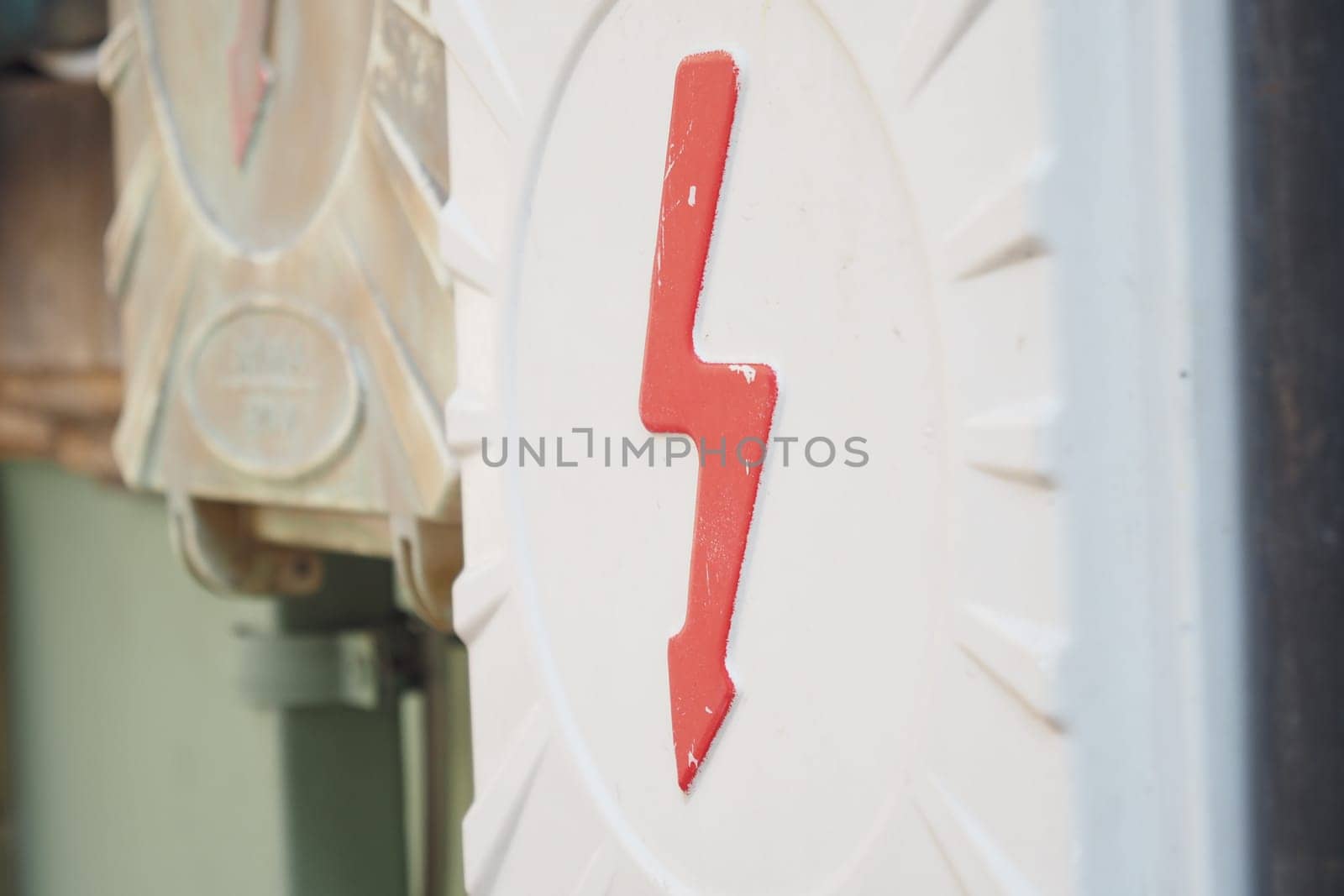 Two electrical boxes with lightning bolt on brick wall.