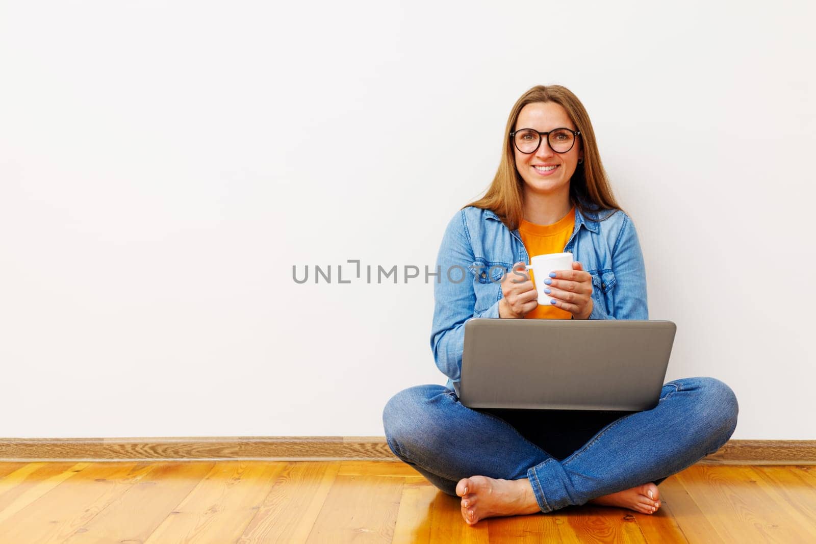 Woman with Laptop and Coffee on Wooden Floor by andreyz