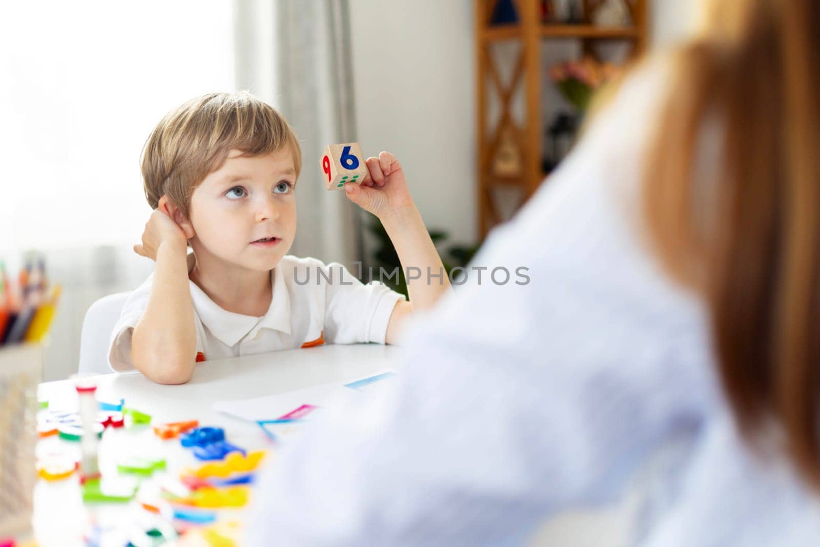 Little boy with number block at table learning math. Early education and cognitive development concept. Design for educational material, banner.