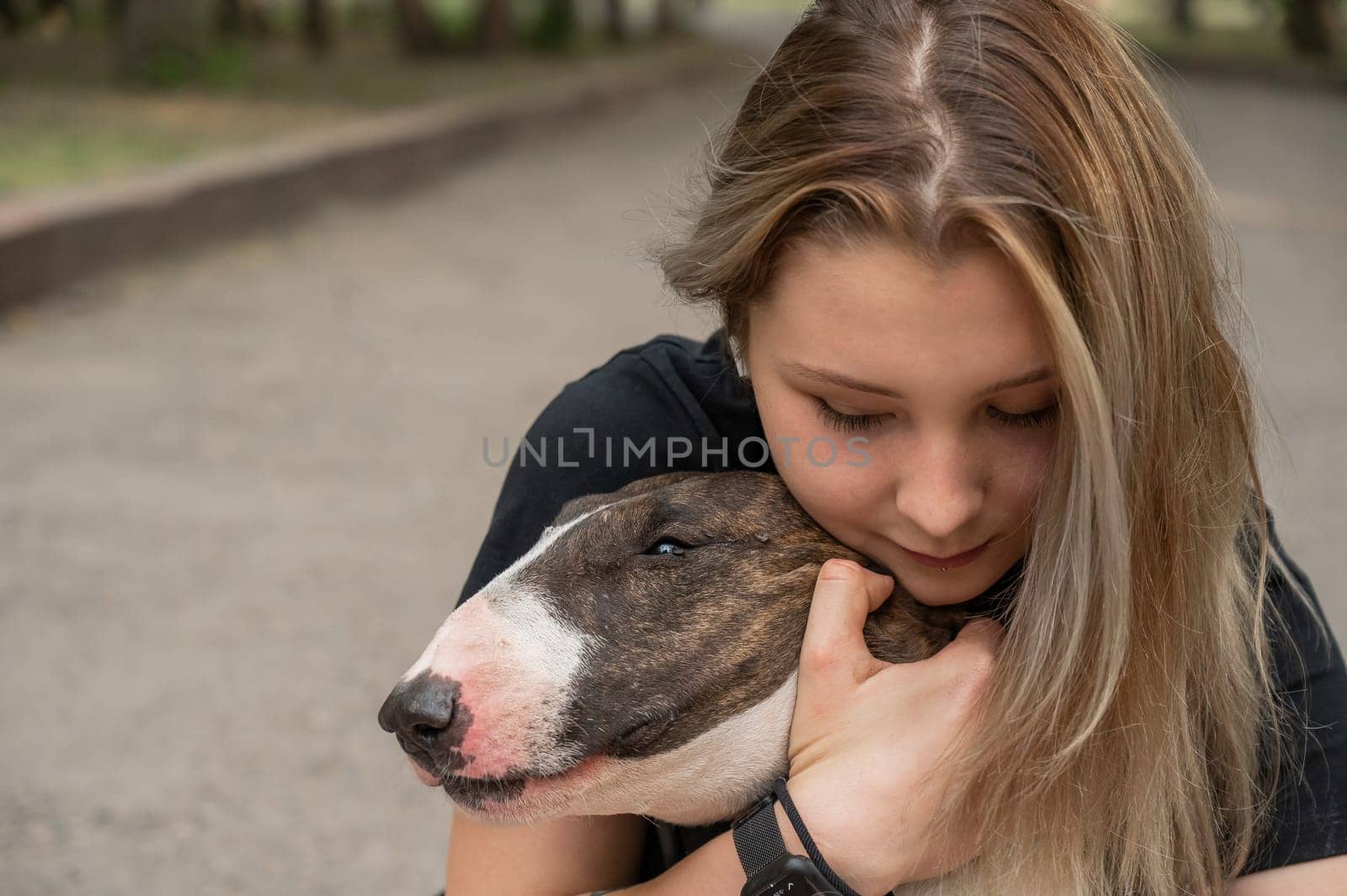 Portrait of caucasian woman hugging her bull terrier dog outdoors