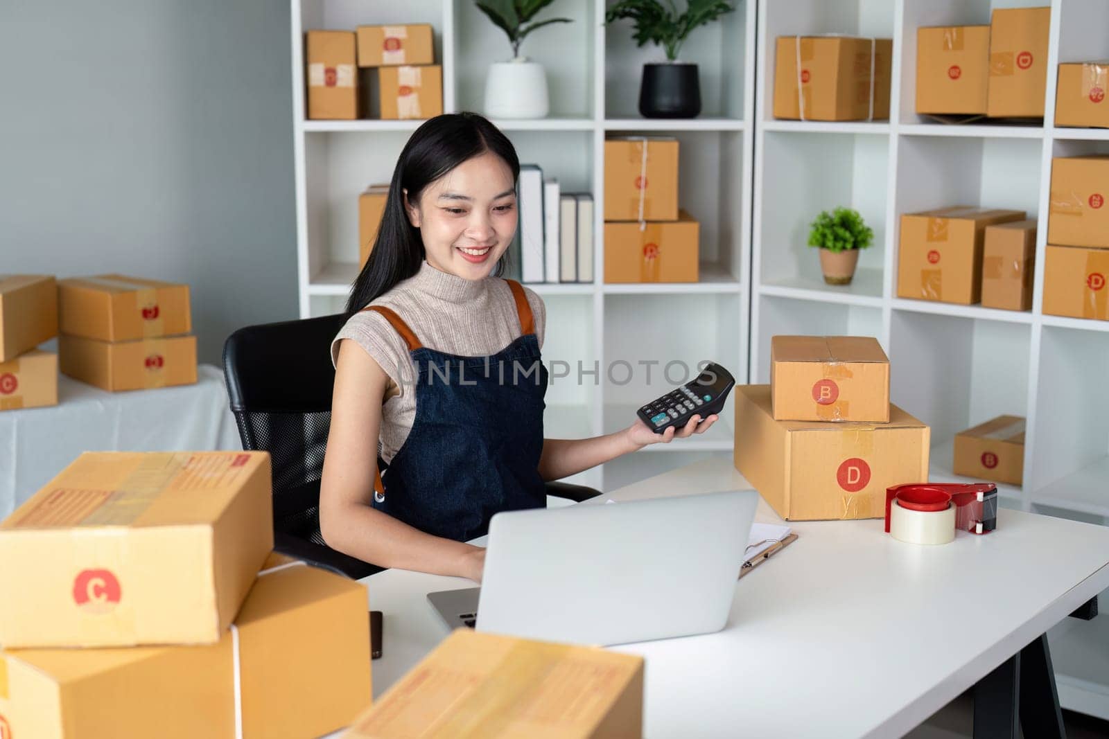 Young business woman asian working online ecommerce shopping at her shop. Young woman sell prepare parcel box of product for deliver to customer. Online selling.