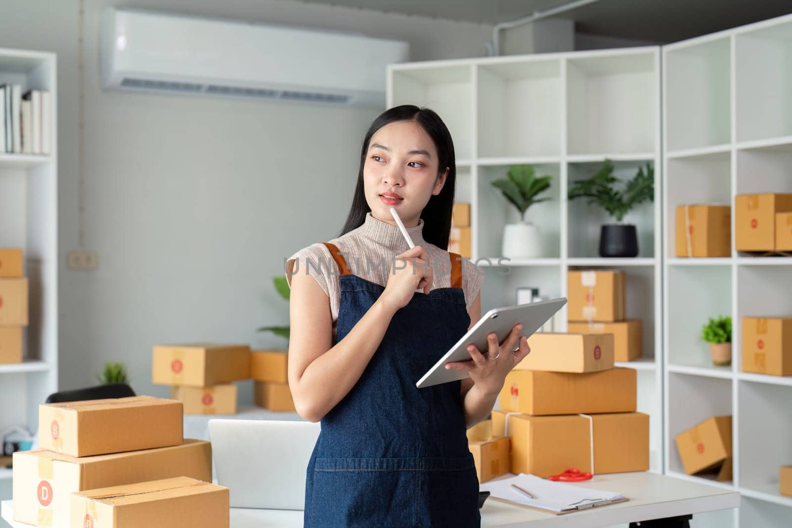 Young business woman asian working online ecommerce shopping at her shop. Young woman sell prepare parcel box of product for deliver to customer. Online selling.