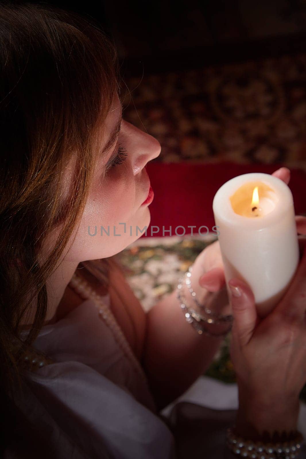 Middle aged beautiful woman holds aromatic candle in hand. Aromatherapy, meditation, healthy life concept. Peace of mind, balance, body care, healthy lifestyle