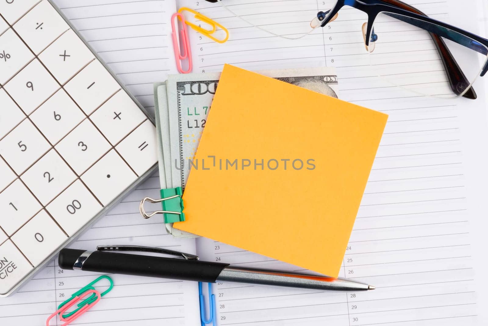 A businessman's workplace with a yellow sticker attached to dollar bills. A place to copy