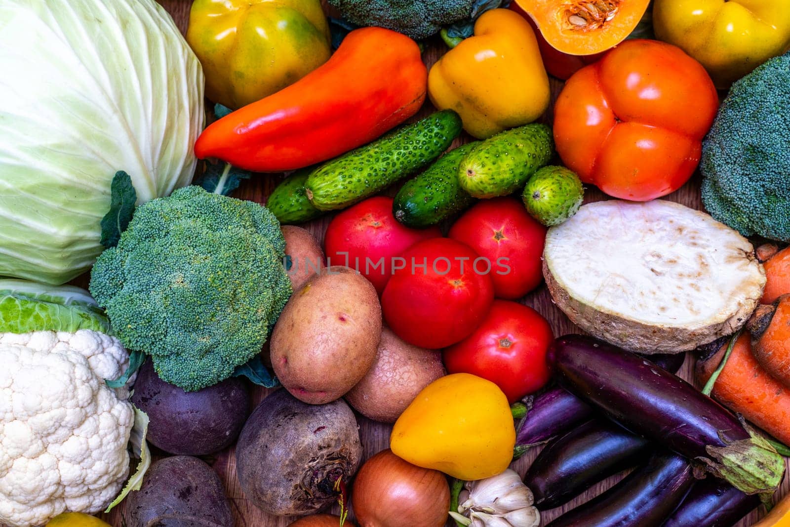 Various vegetables are laid out on a wooden table. Large assortment of vegetables food. pumpkin cabbage broccoli pepper tomatoes carrots and others.