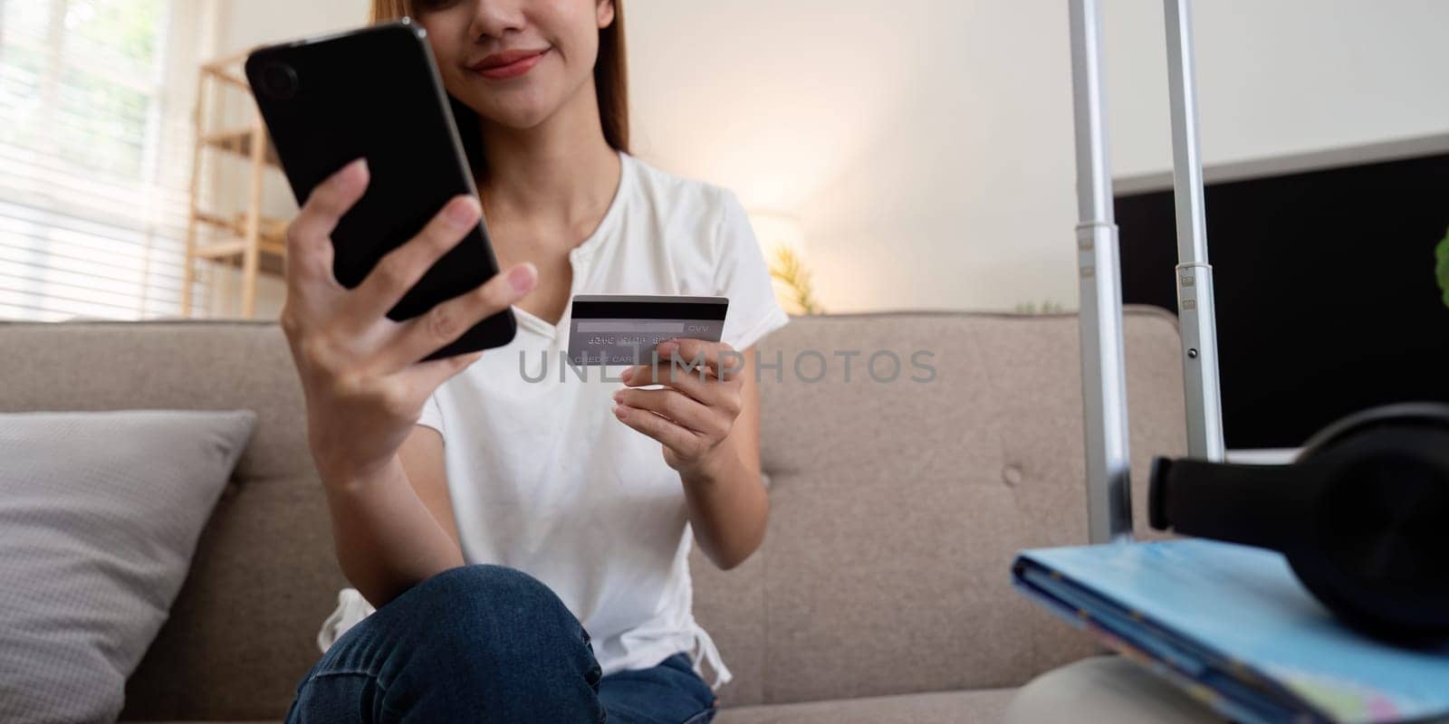 Asian woman using credit card booking flight tickets and hotel at home. Planning a trip and online booking, Summer vacation concept by nateemee