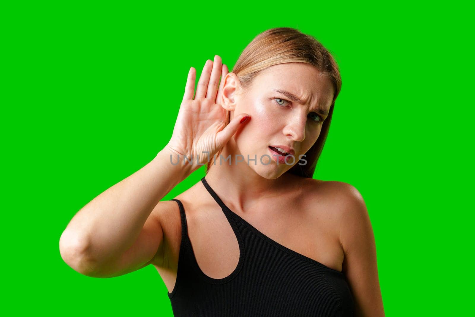 Young Woman in Black Top Holding Hand to Ear against green background