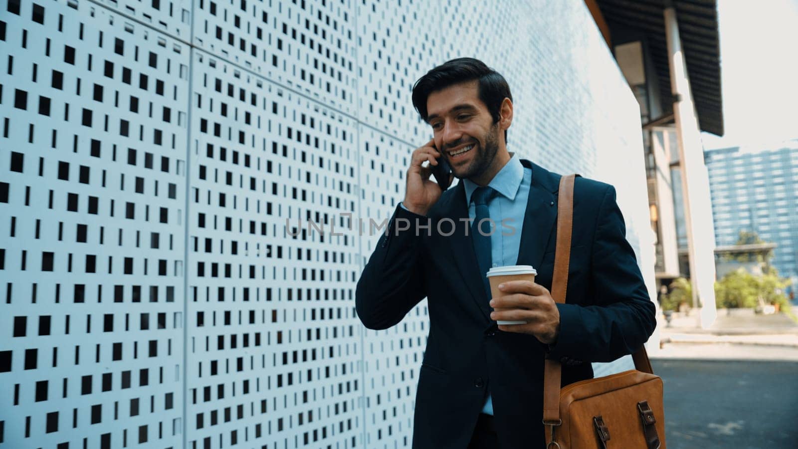 Smart business man using phone to talking about business investment. Happy manager walking at street while talking on smart phone to discuss business plan or marketing strategy or working. Exultant.