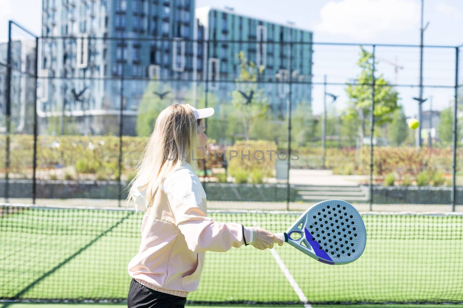 Young sporty woman performing basic strokes during paddle tennis group training by Andelov13
