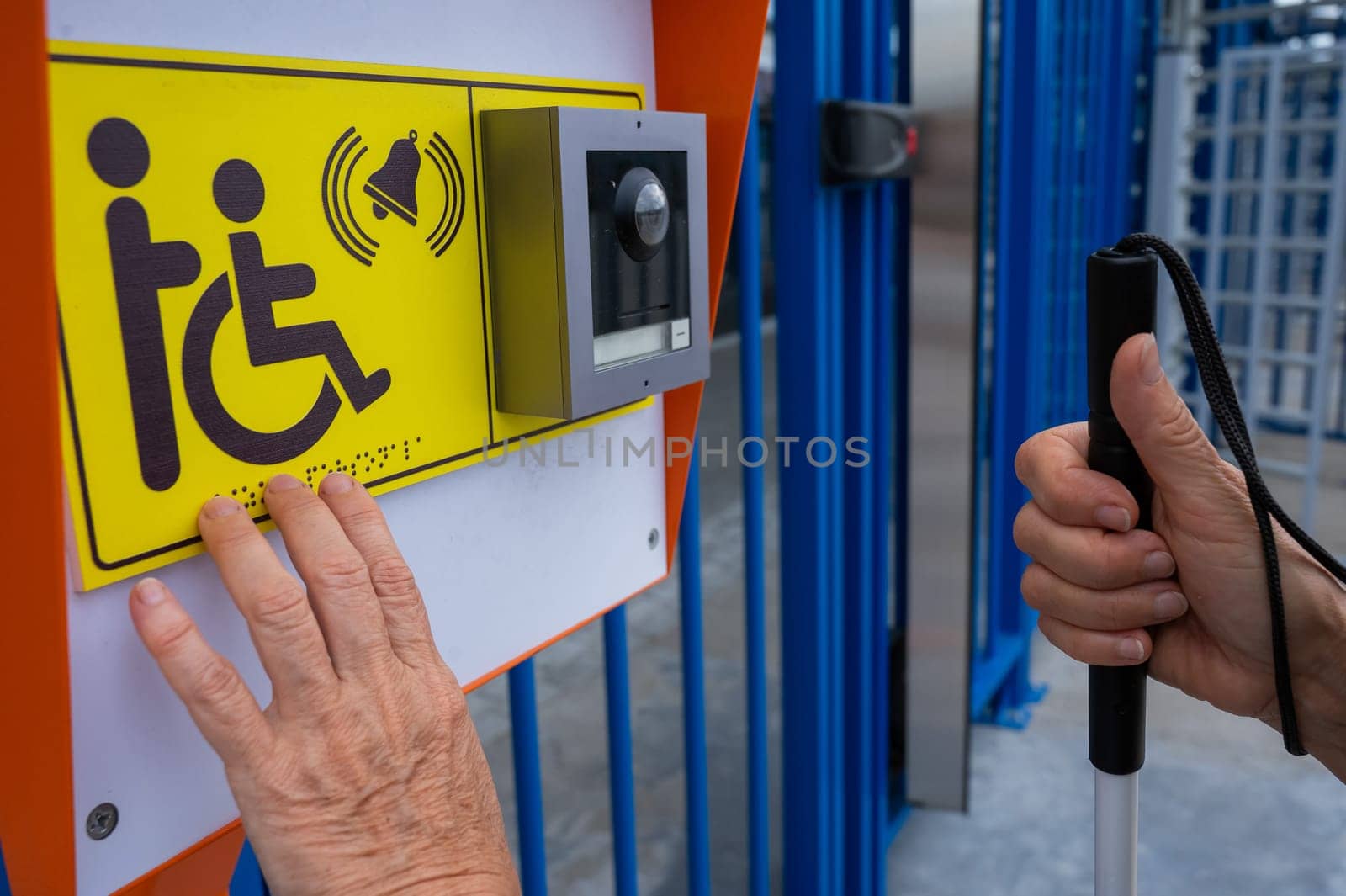 Close-up of the hands of a blind elderly woman reading a text in braille. Button for calling help for people with disabilities