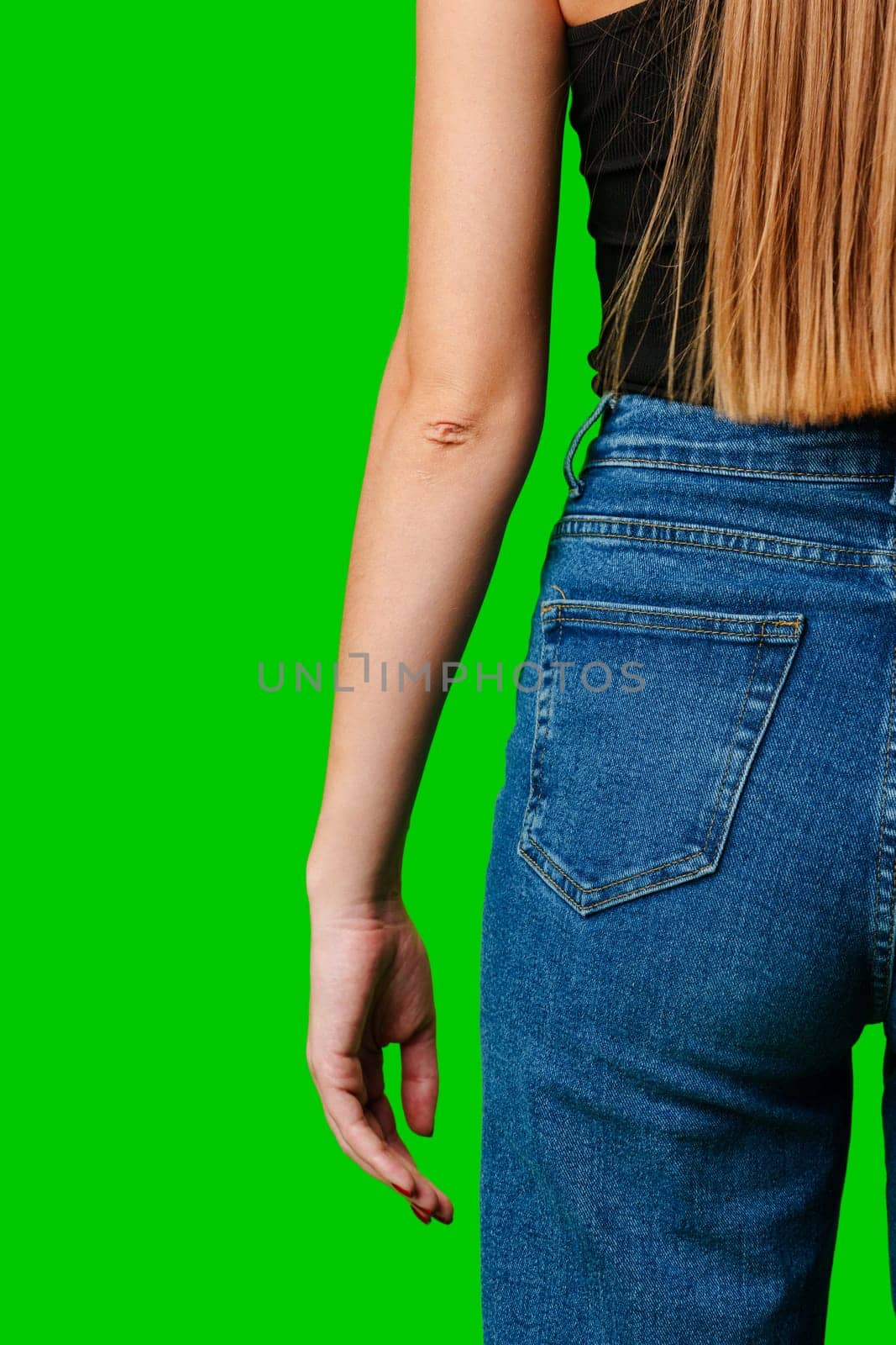 Woman Standing Sideways Wearing Denim Jeans Against a Green Background by Fabrikasimf