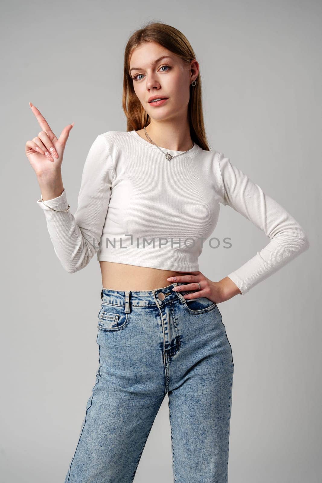 Young Woman Gesturing With Her Finger While Speaking Against a Gray Background by Fabrikasimf
