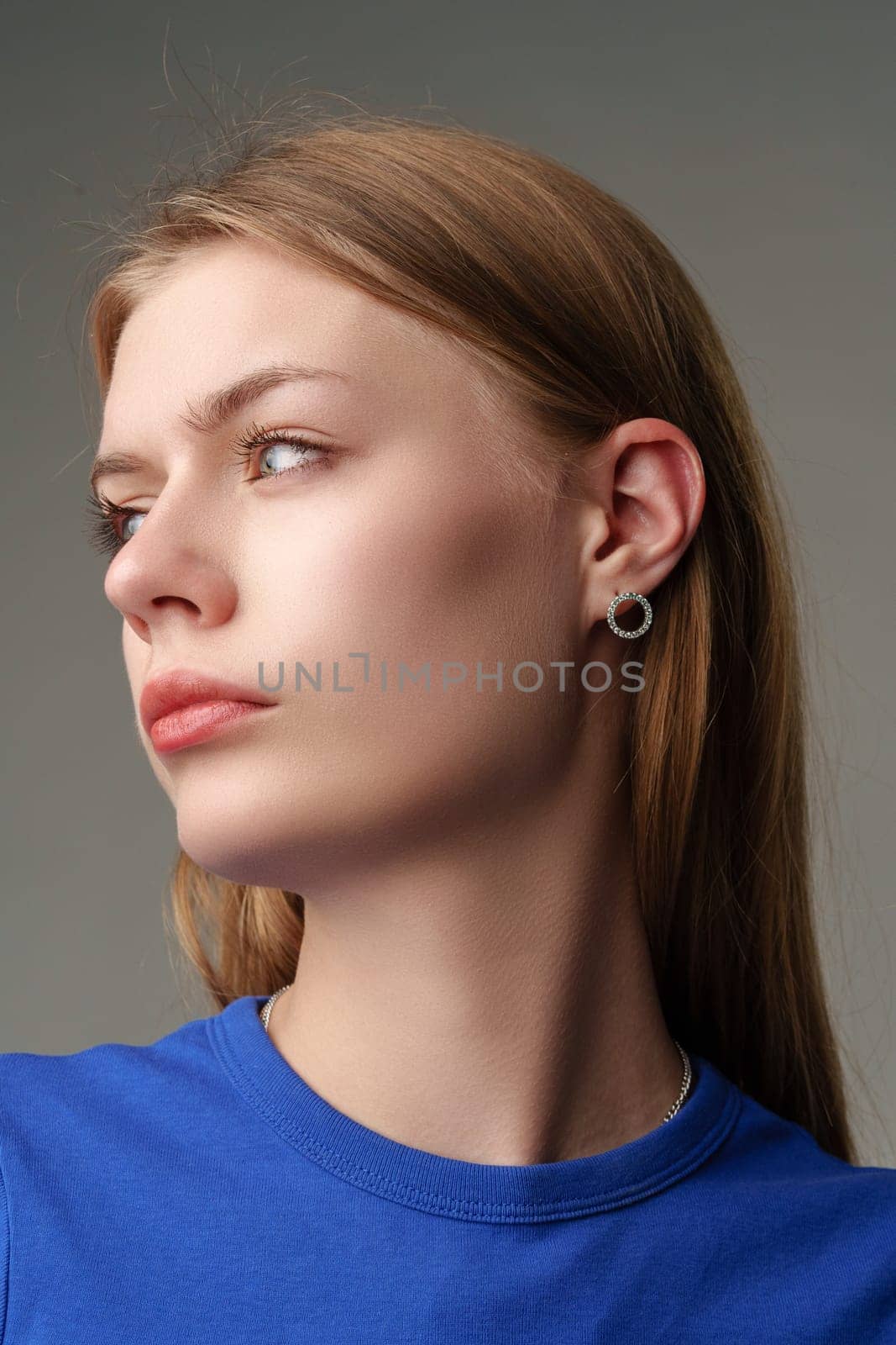 Portrait of Young Woman in Blue Top on gray background close up