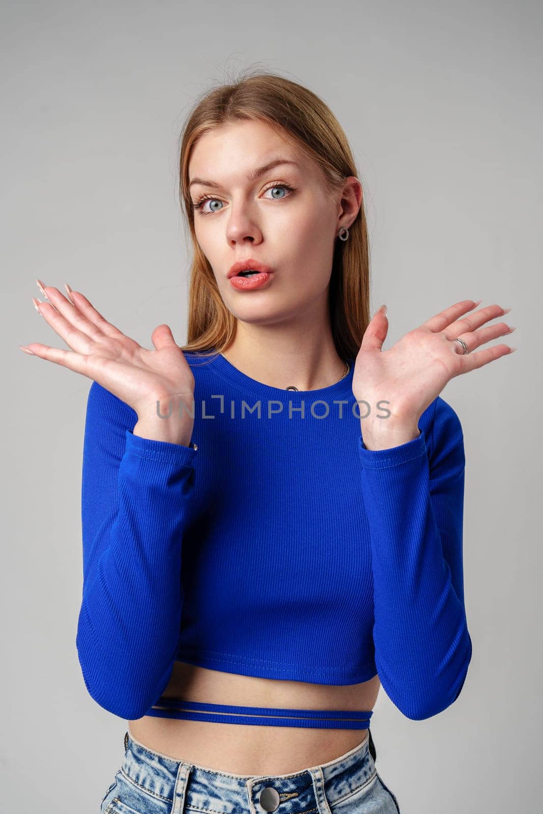 Young Woman in Blue Top Holding Out Hands in studio