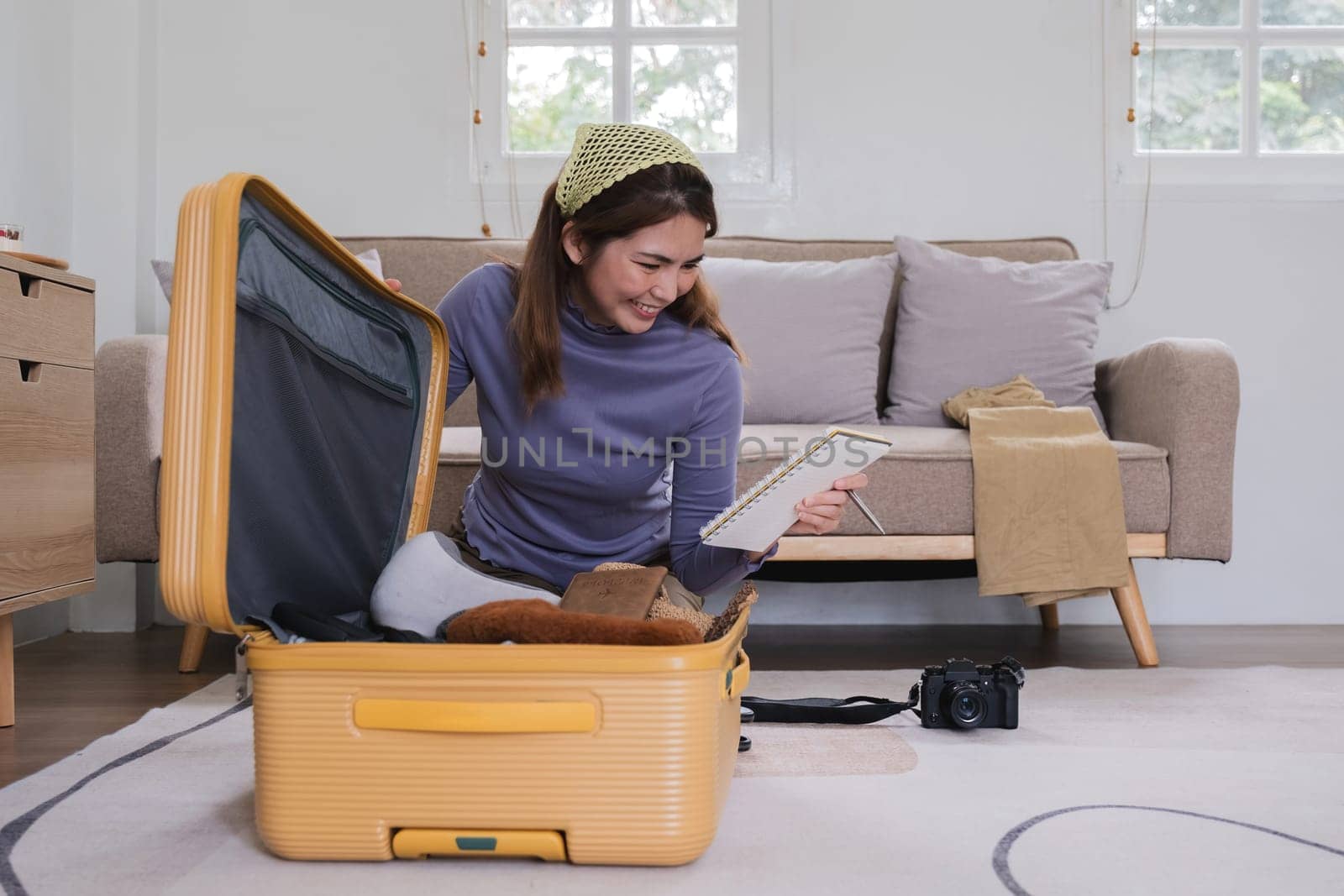 Asian woman packs her suitcase, packing her belongings, clothes and travel documents before going on vacation. Lifestyle concept by wichayada