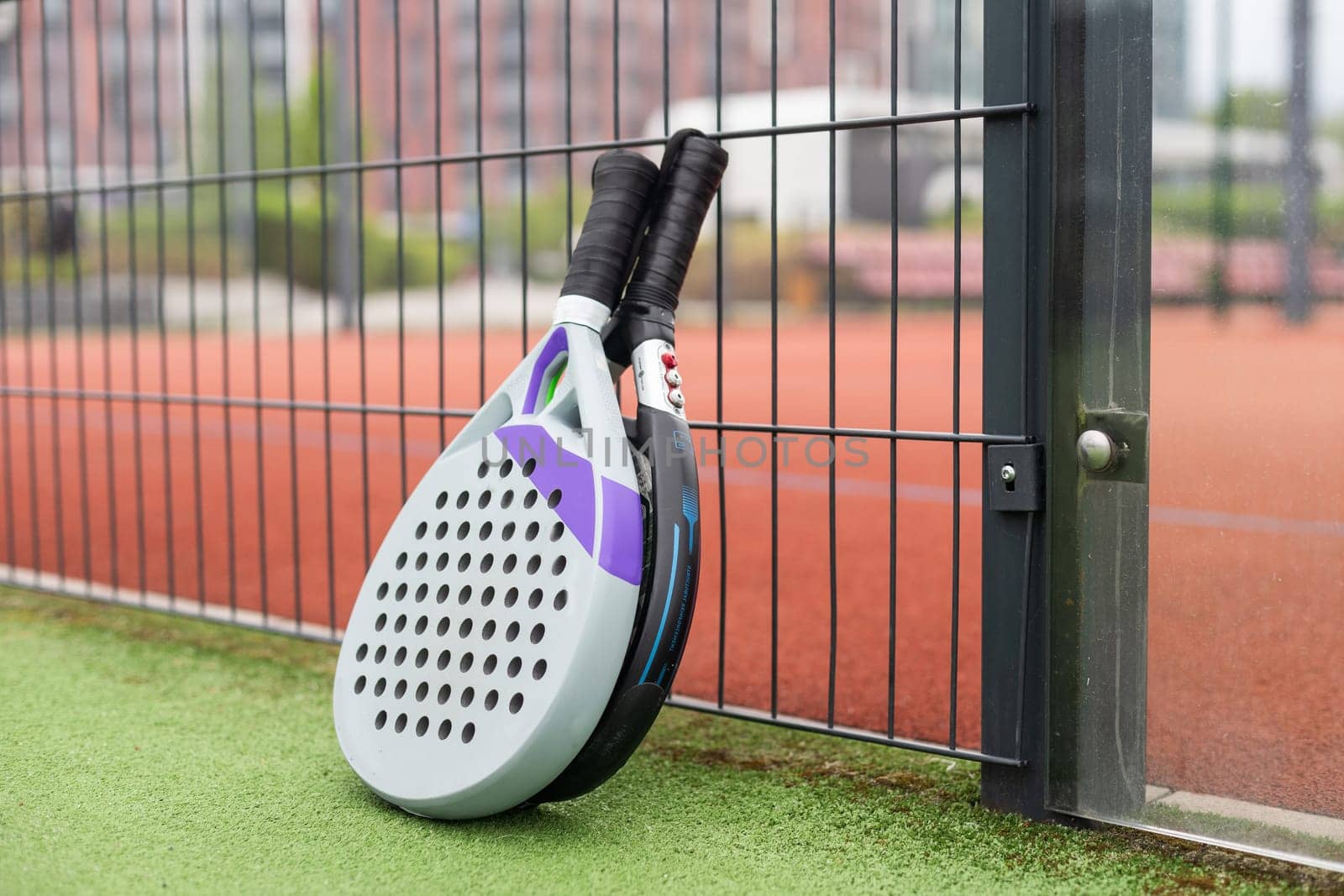 Padel racket and padel ball on a green court in the sunset. High quality photo
