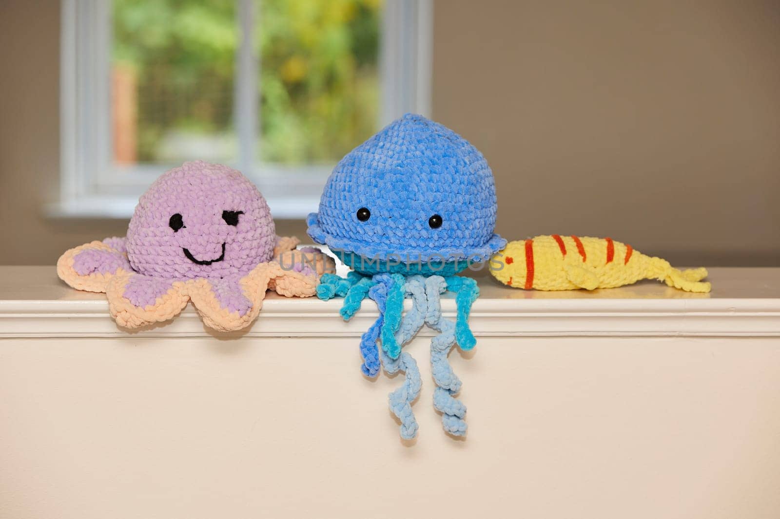 Cute knitted toy octopus, jellyfish and fish at home.
