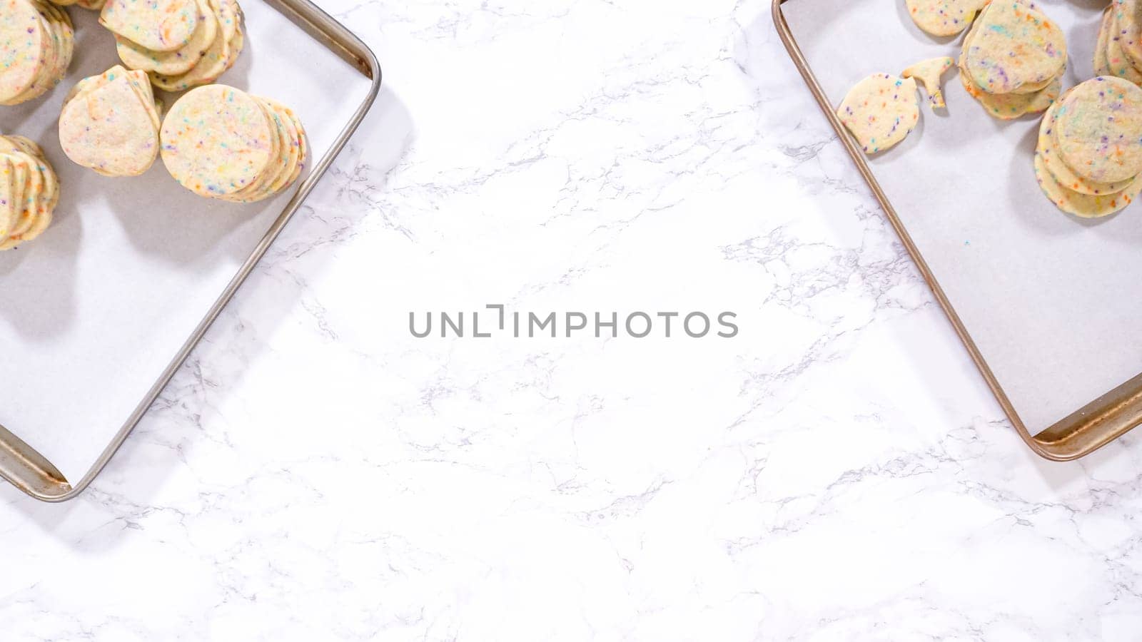 Flat lay. With precision, the woman is carefully arranging the sugar cookies, filled with dough-mixed sprinkles, into a rustic brown paper box.