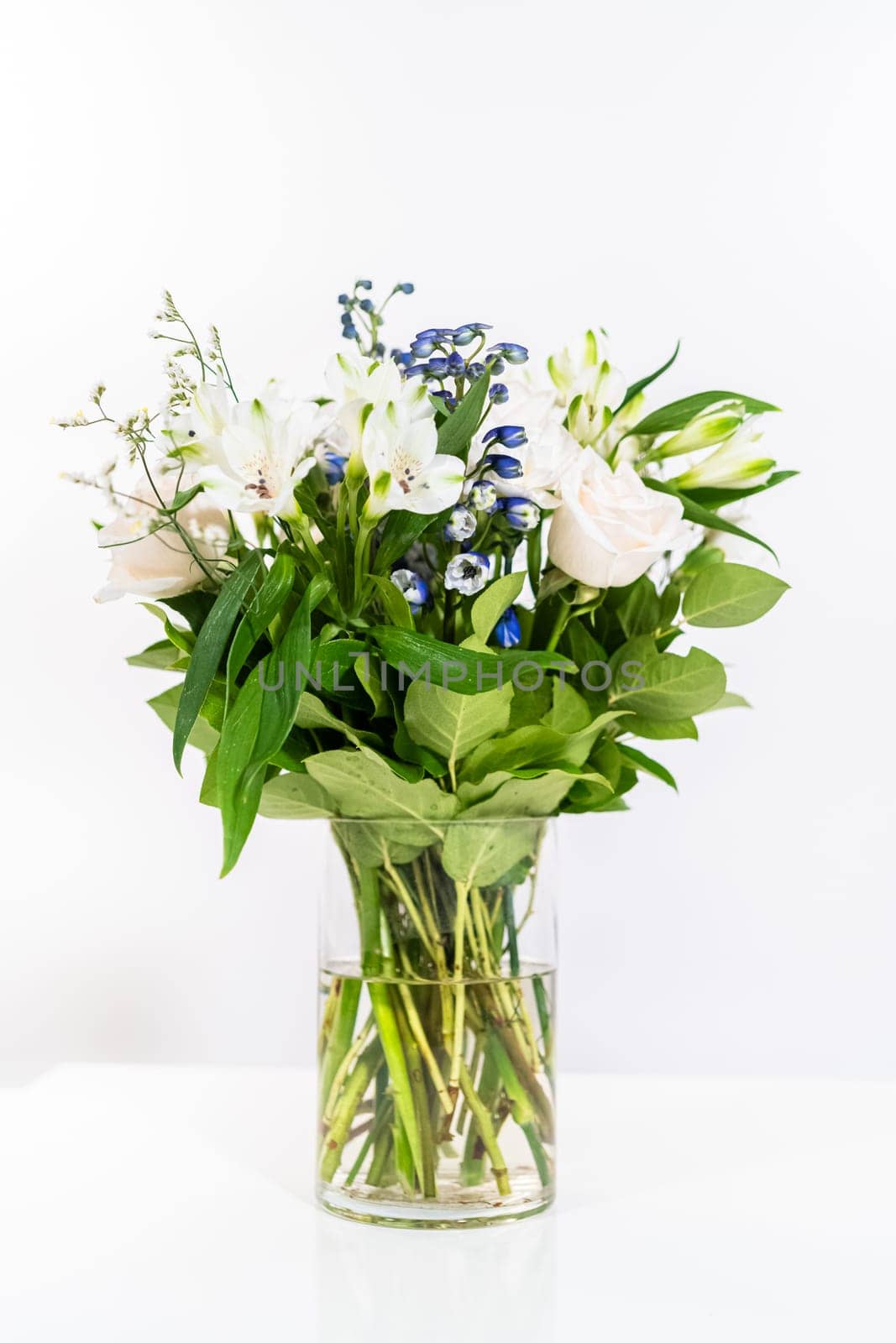 A stunning bouquet featuring fresh white roses and assorted flowers gracefully arranged in a vase, exuding timeless beauty.